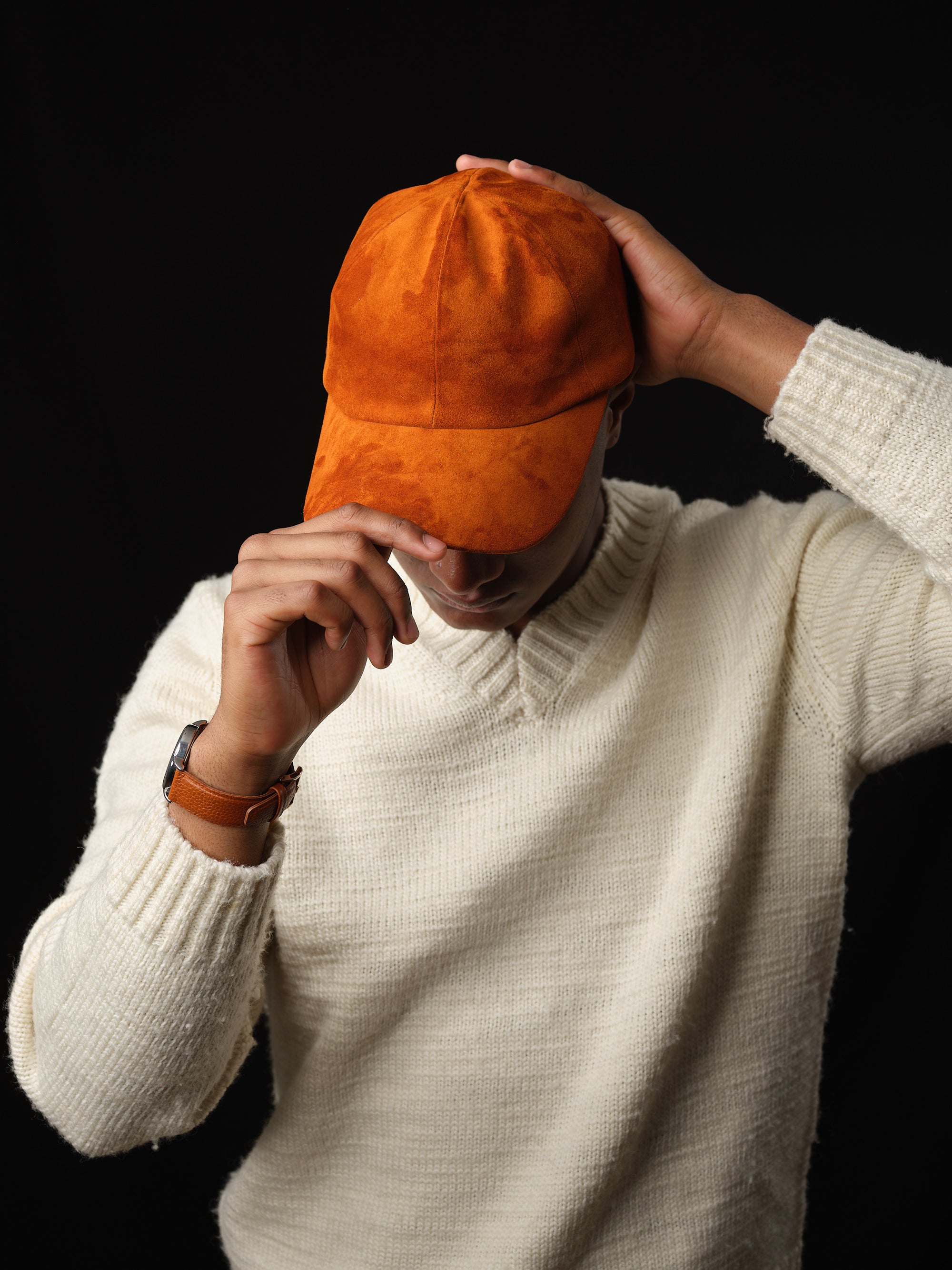 Close-up of a tan suede baseball cap with ear flaps, handcrafted by Capra Leather