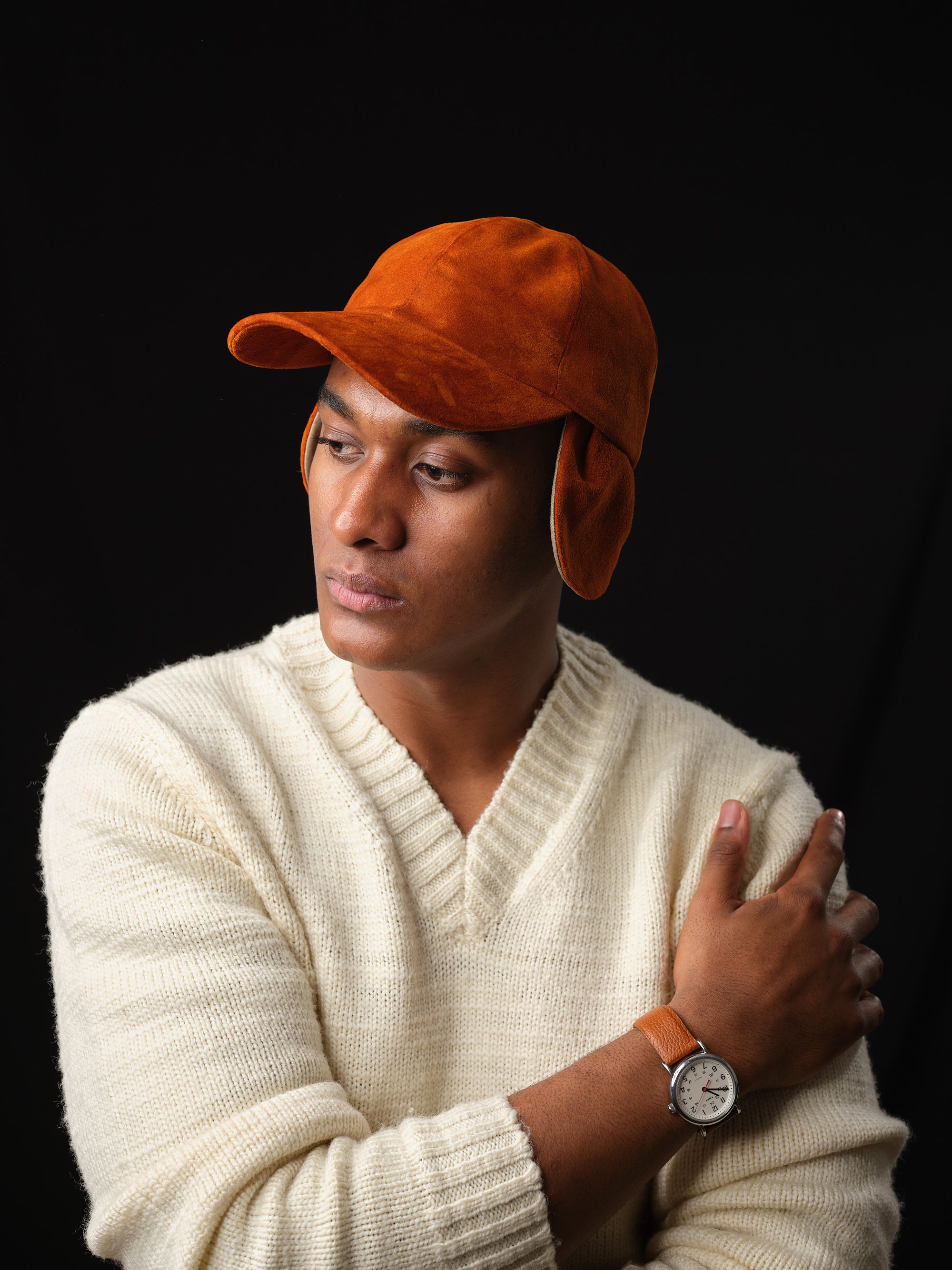 Man wearing a tan suede baseball cap with ear flaps, handcrafted by Capra Leather