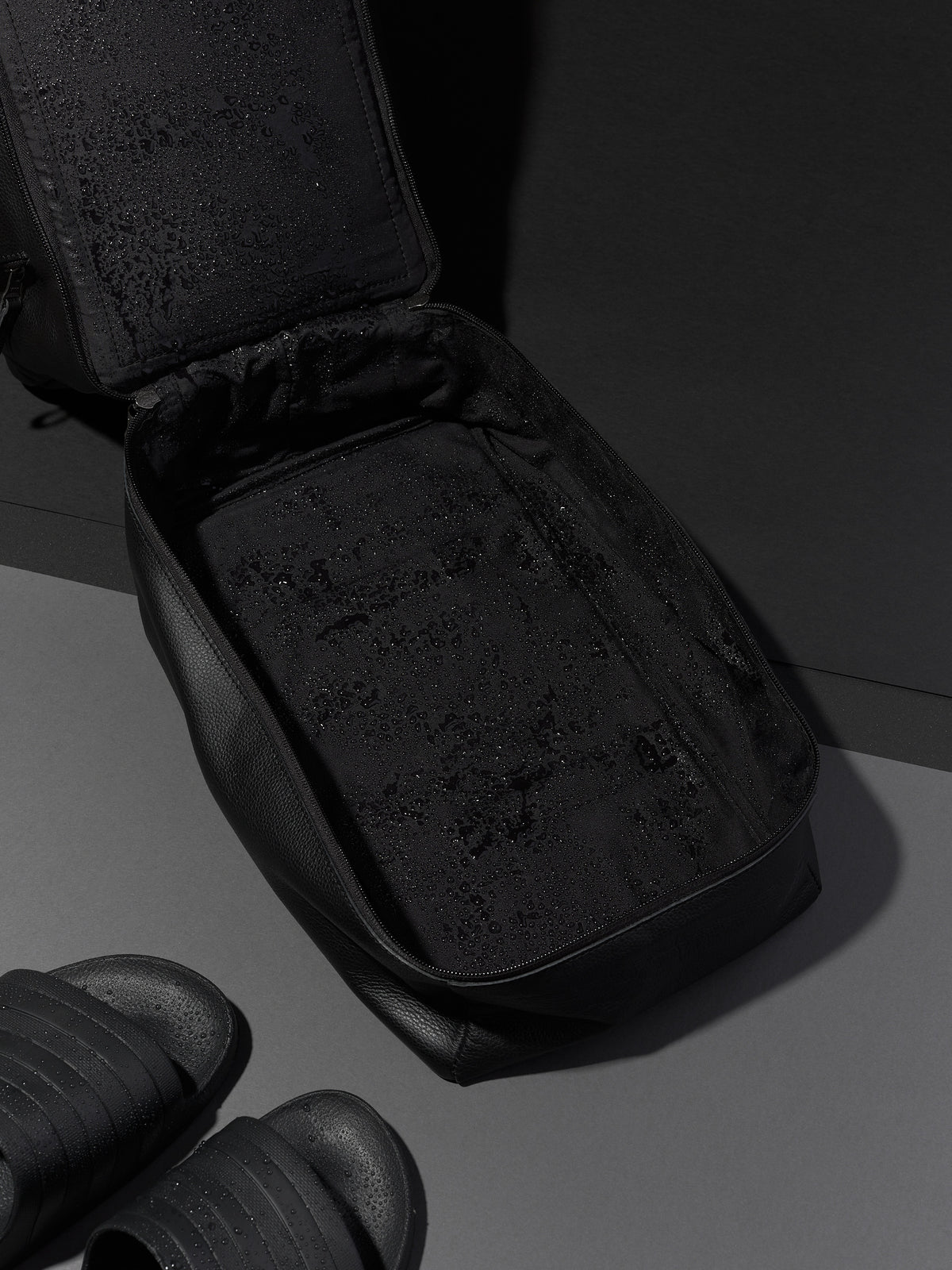 Black Capra Leather duffel bag, unzipped to show the empty interior with water-resistant lining.