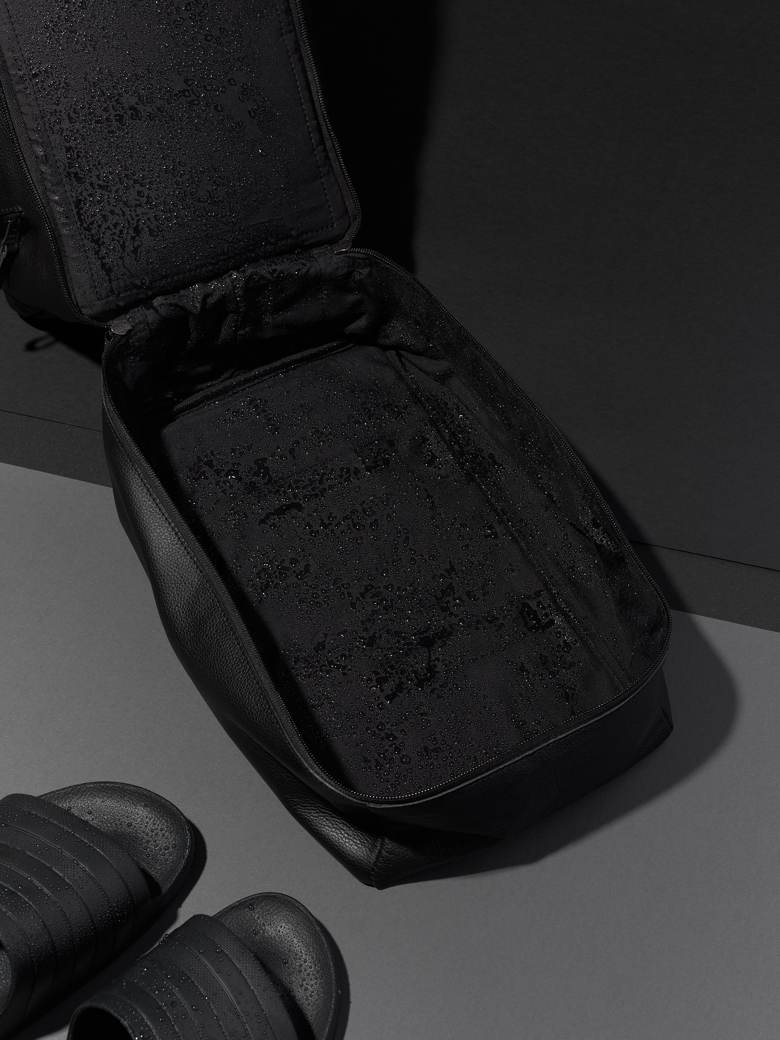 Black Capra Leather duffel bag, unzipped to show the empty interior with water-resistant lining.