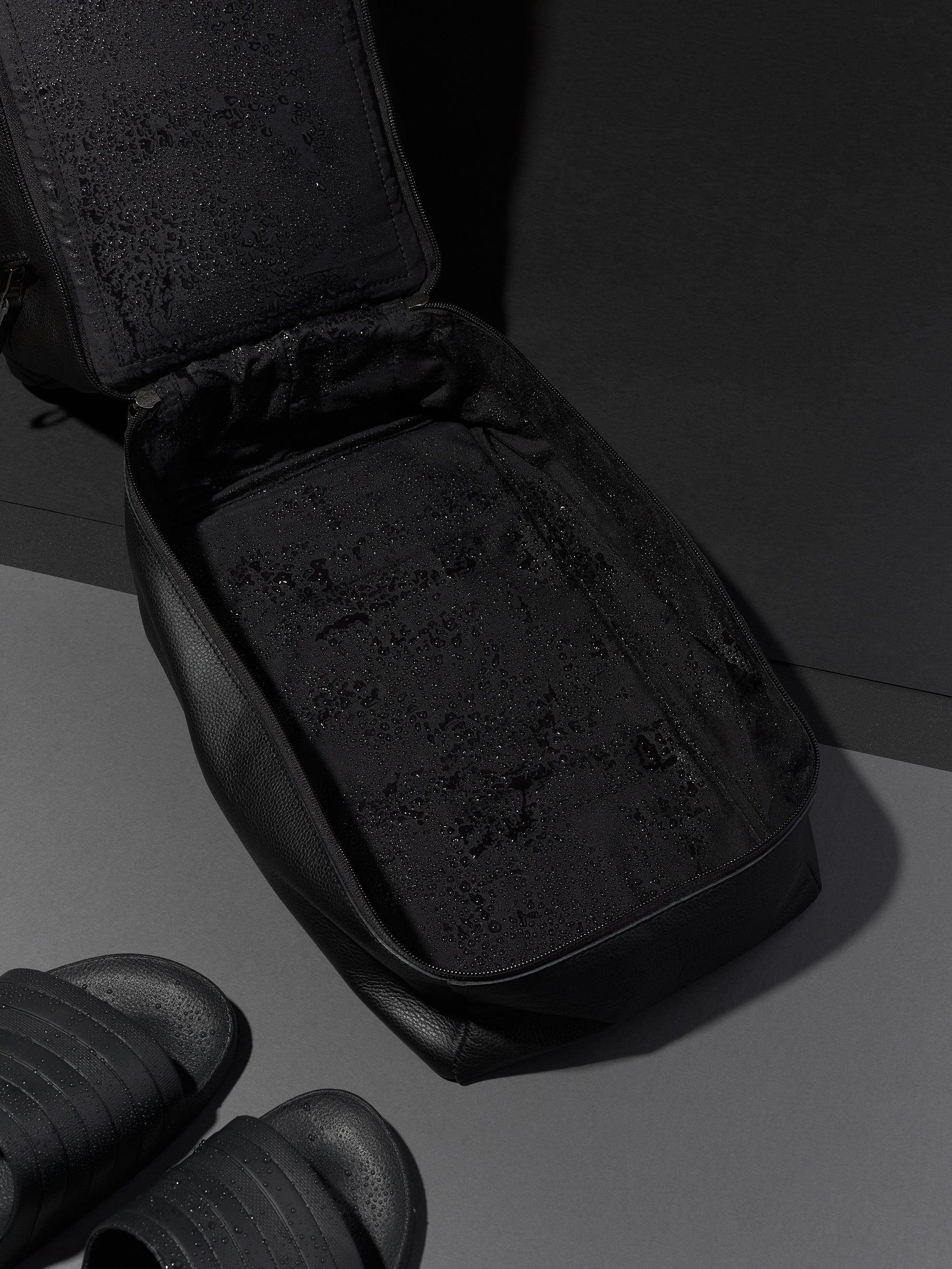 Black Capra Leather duffel bag, unzipped to show the empty interior with water-resistant lining.