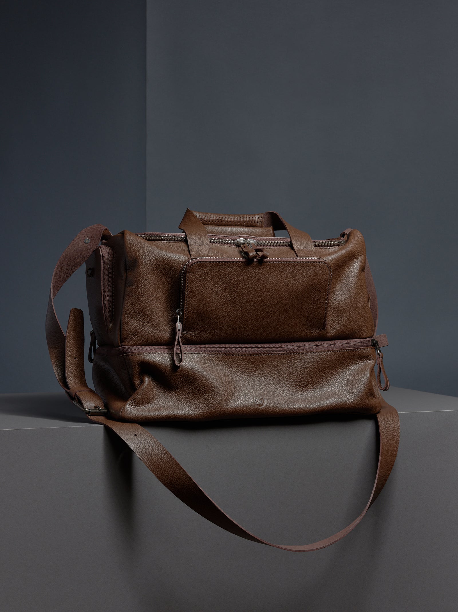 A man in athletic wear holding the brown leather Ventra Holdall by its top handles, showcasing it as a luxury sports bag.