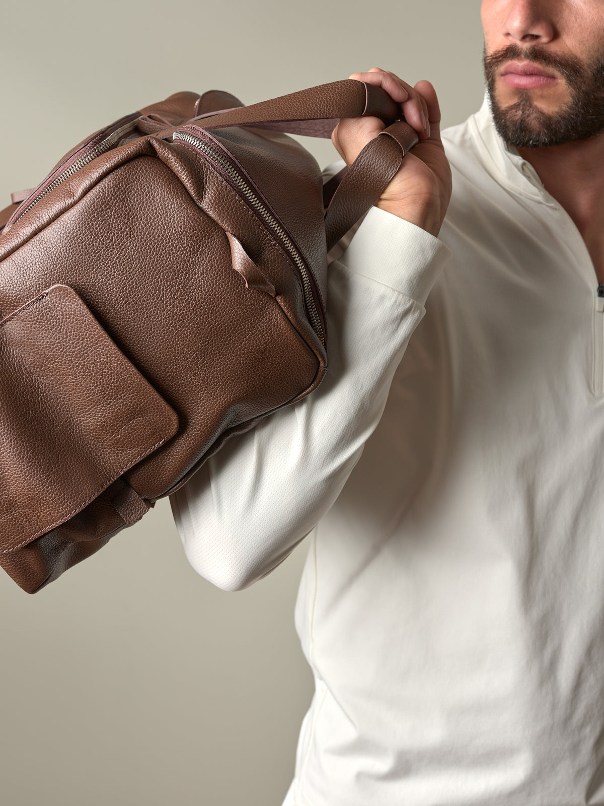Close-up of a man holding the brown pebbled leather Ventra Holdall, displaying its rich texture and quality handles.