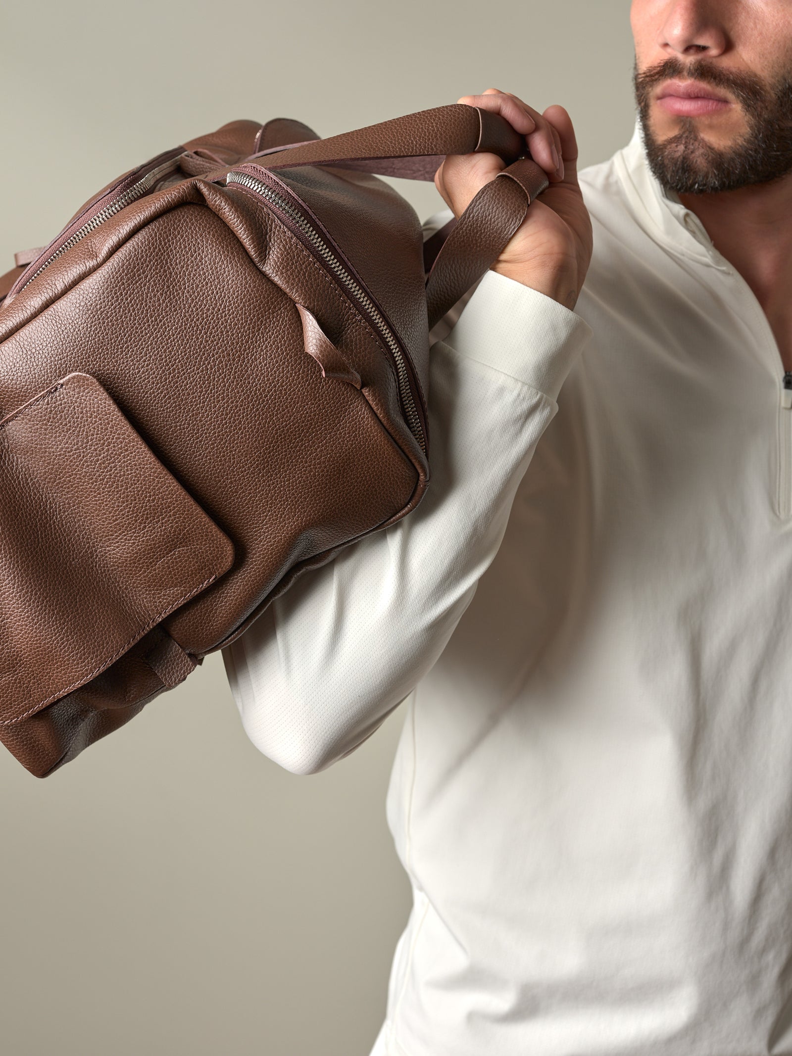 Close-up of a man holding the brown pebbled leather Ventra Holdall, displaying its rich texture and quality handles.