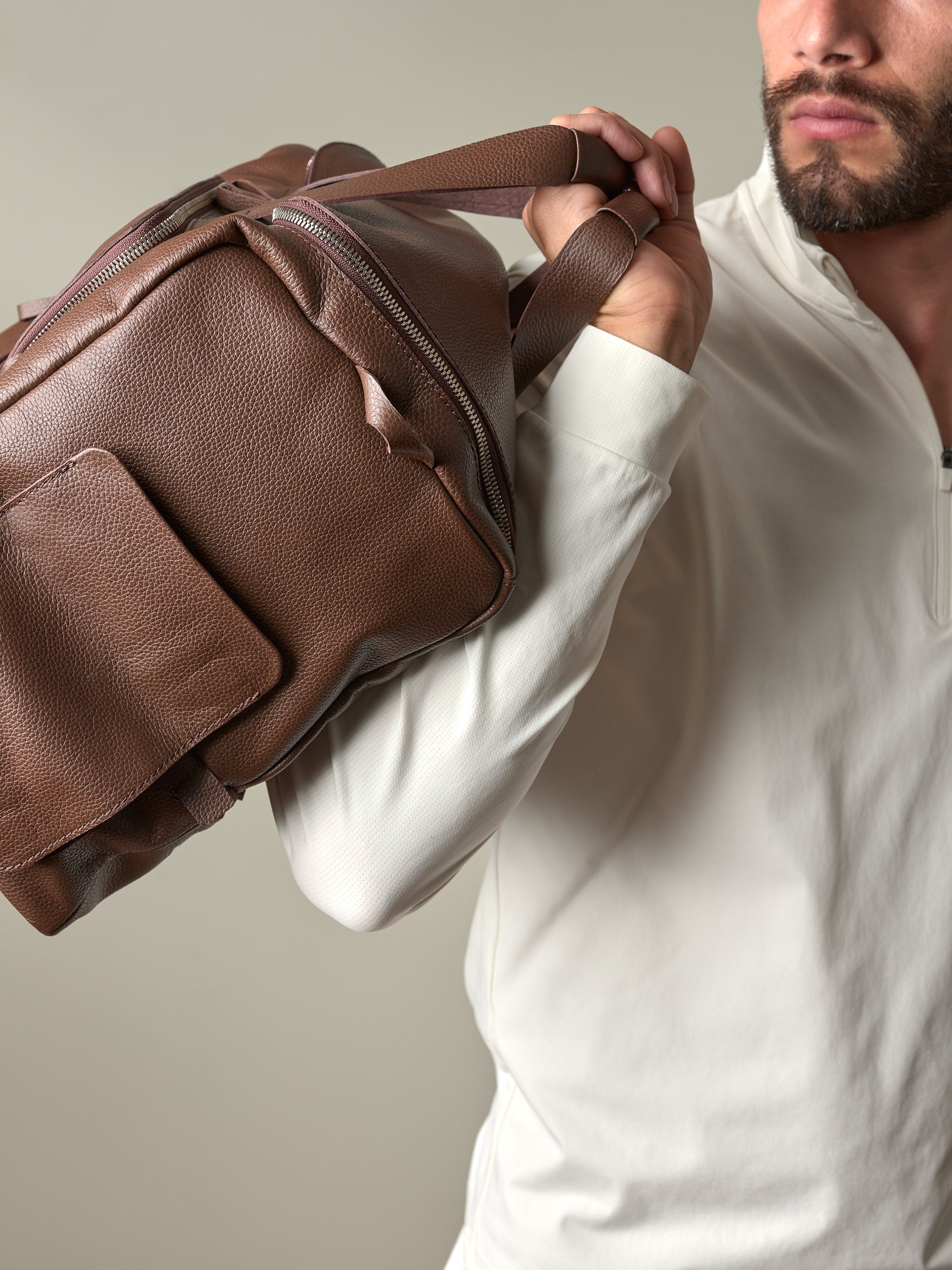 Close-up of a man holding the brown pebbled leather Ventra Holdall, displaying its rich texture and quality handles.