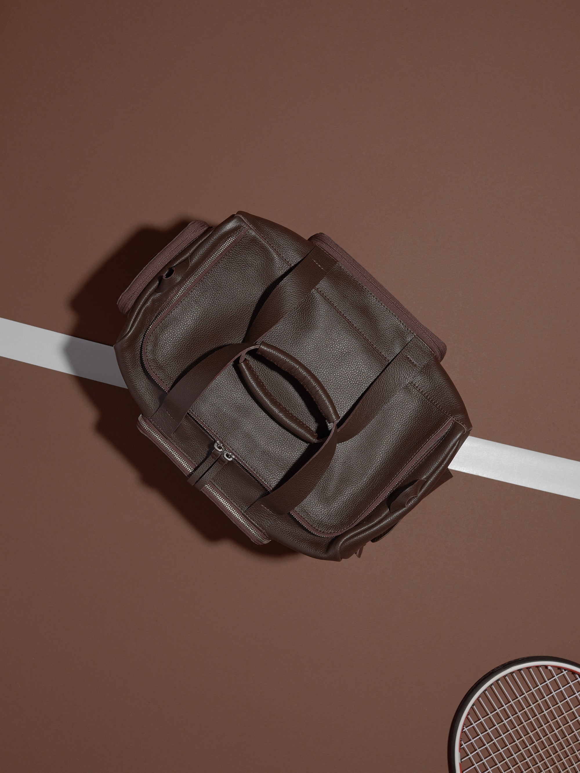 The Ventra Holdall duffle bag lying open on a tennis court, with a white line and tennis racket visible.