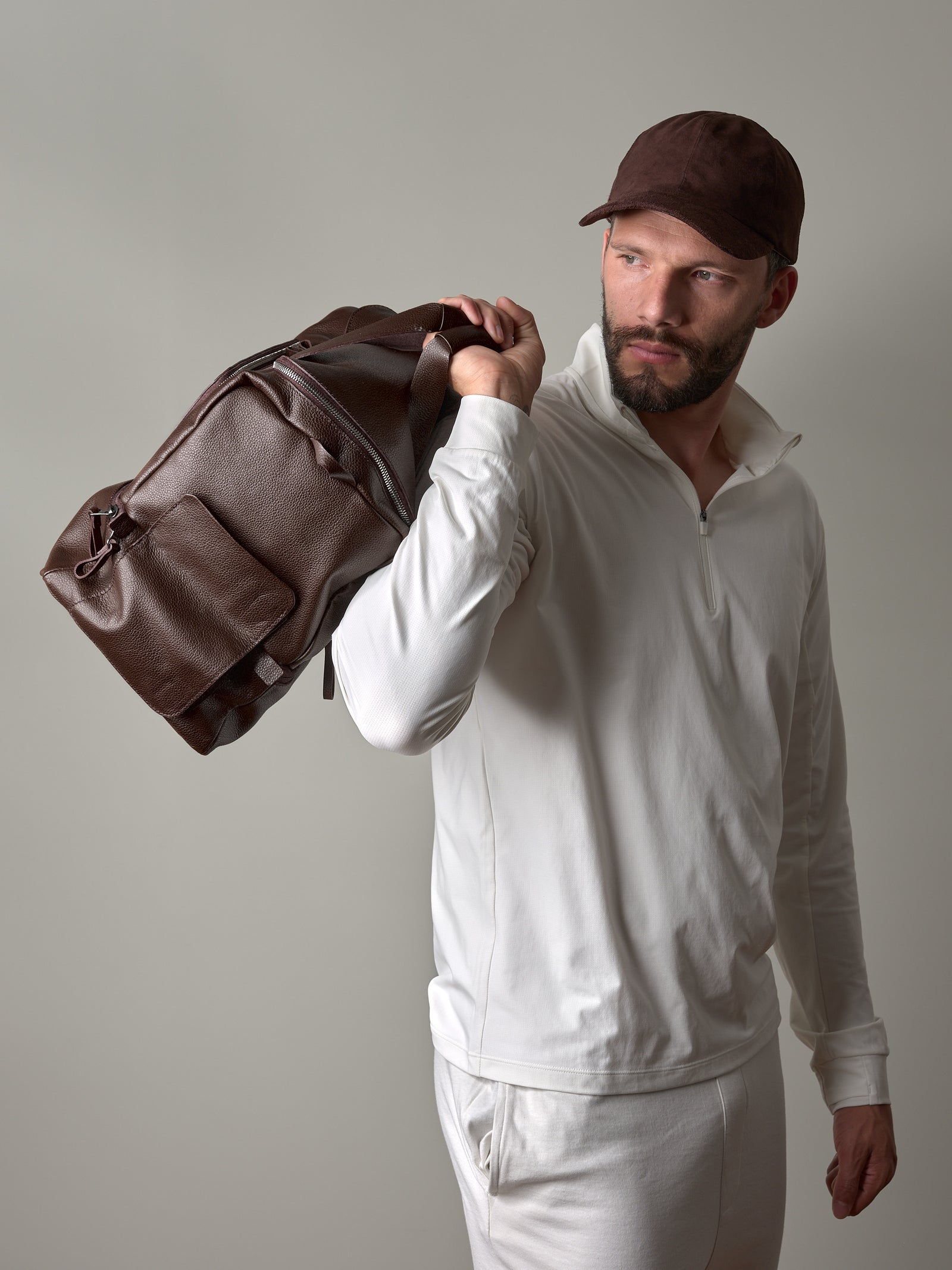 The Capra Leather Ventra Holdall, a dark brown leather duffel bag, shown on a brown background.