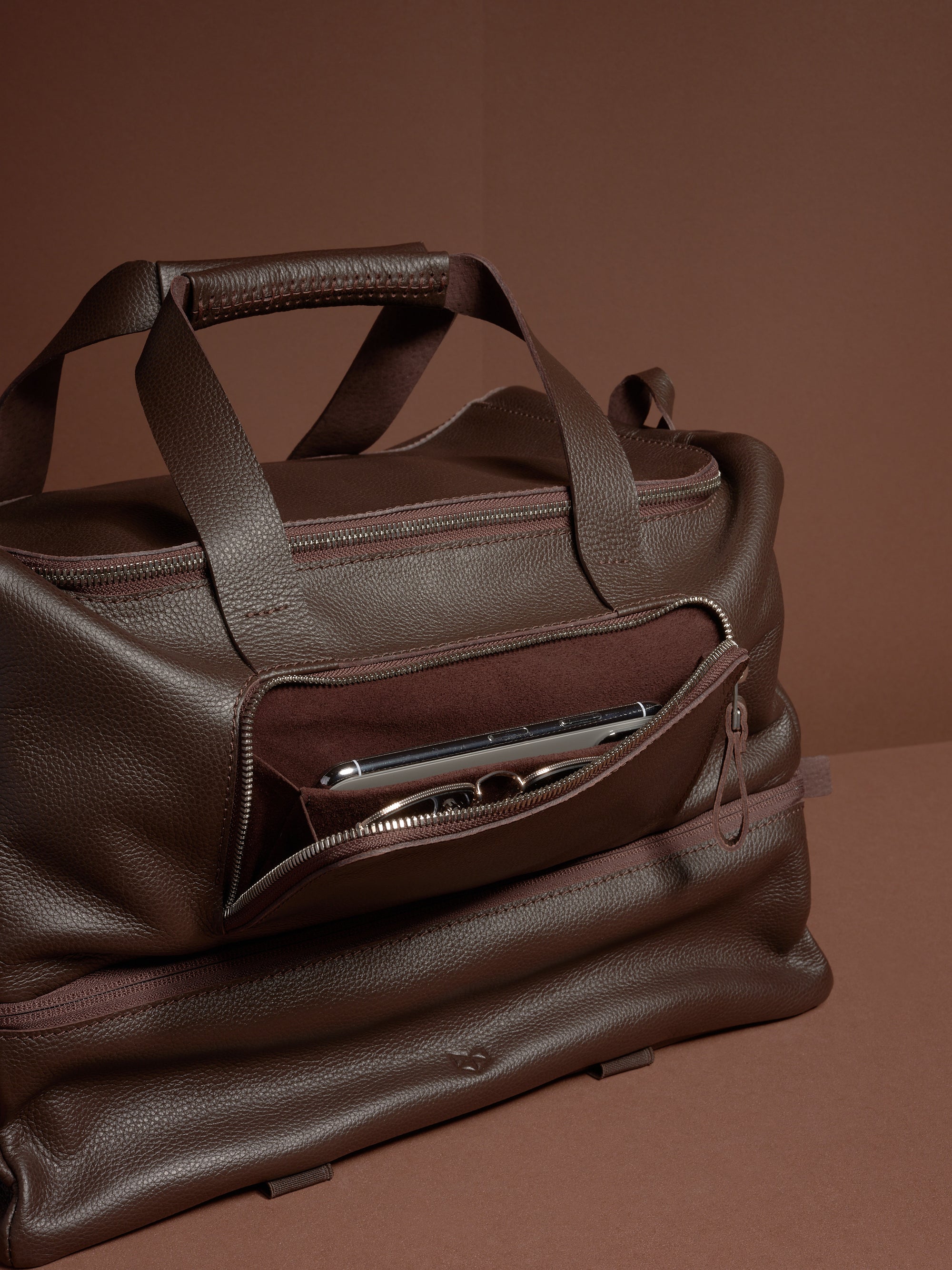 The Ventra Holdall bag with a front pocket unzipped, showing a smartphone and glasses inside.