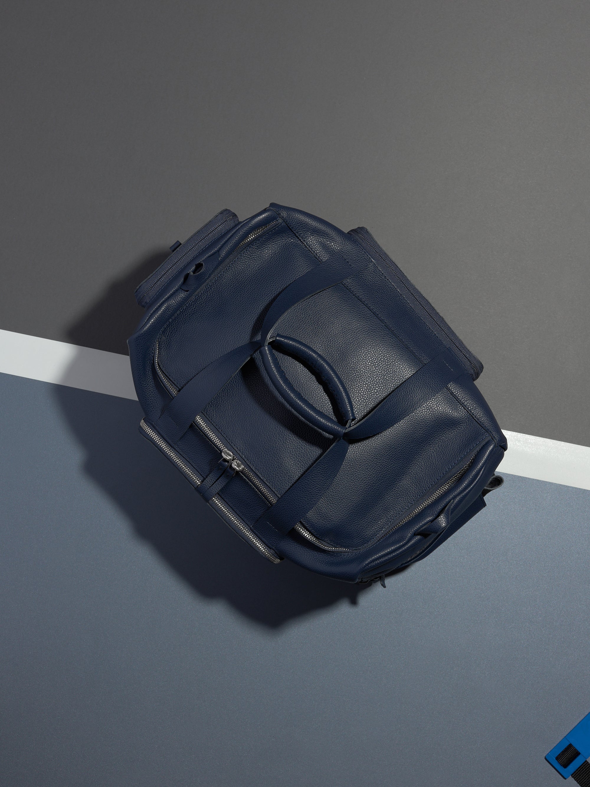 The Ventra Holdall duffle bag lying on a tennis court with a white line and blue background.