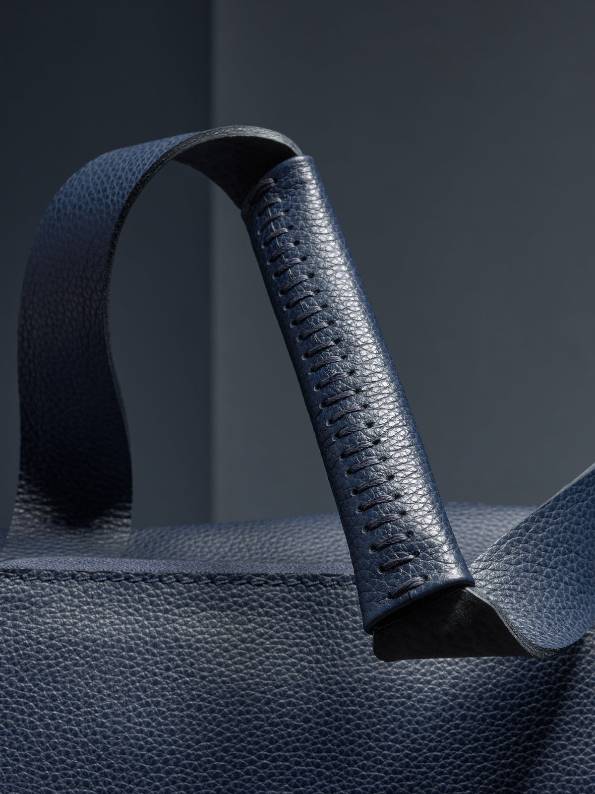 Close-up of the Ventra Holdall's handle, showcasing hand-stitched leather detail.