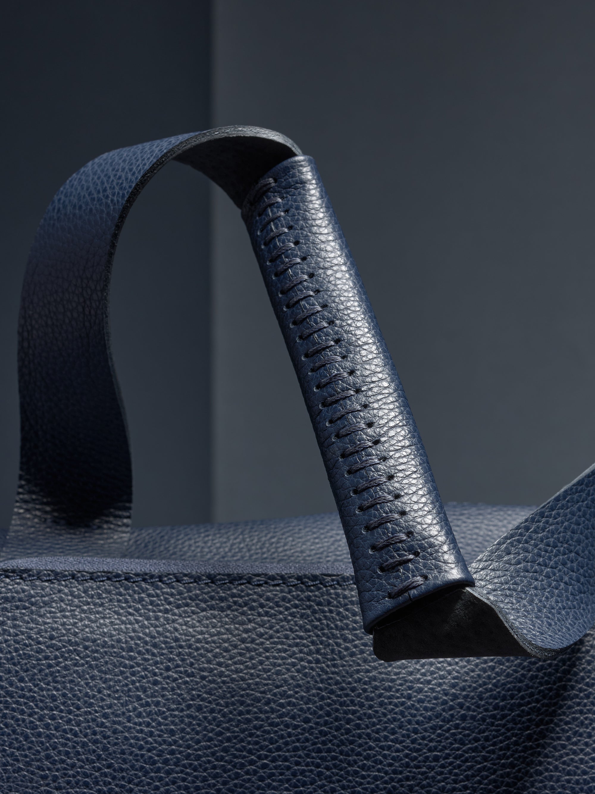 Close-up of the Ventra Holdall's handle, showcasing hand-stitched leather detail.