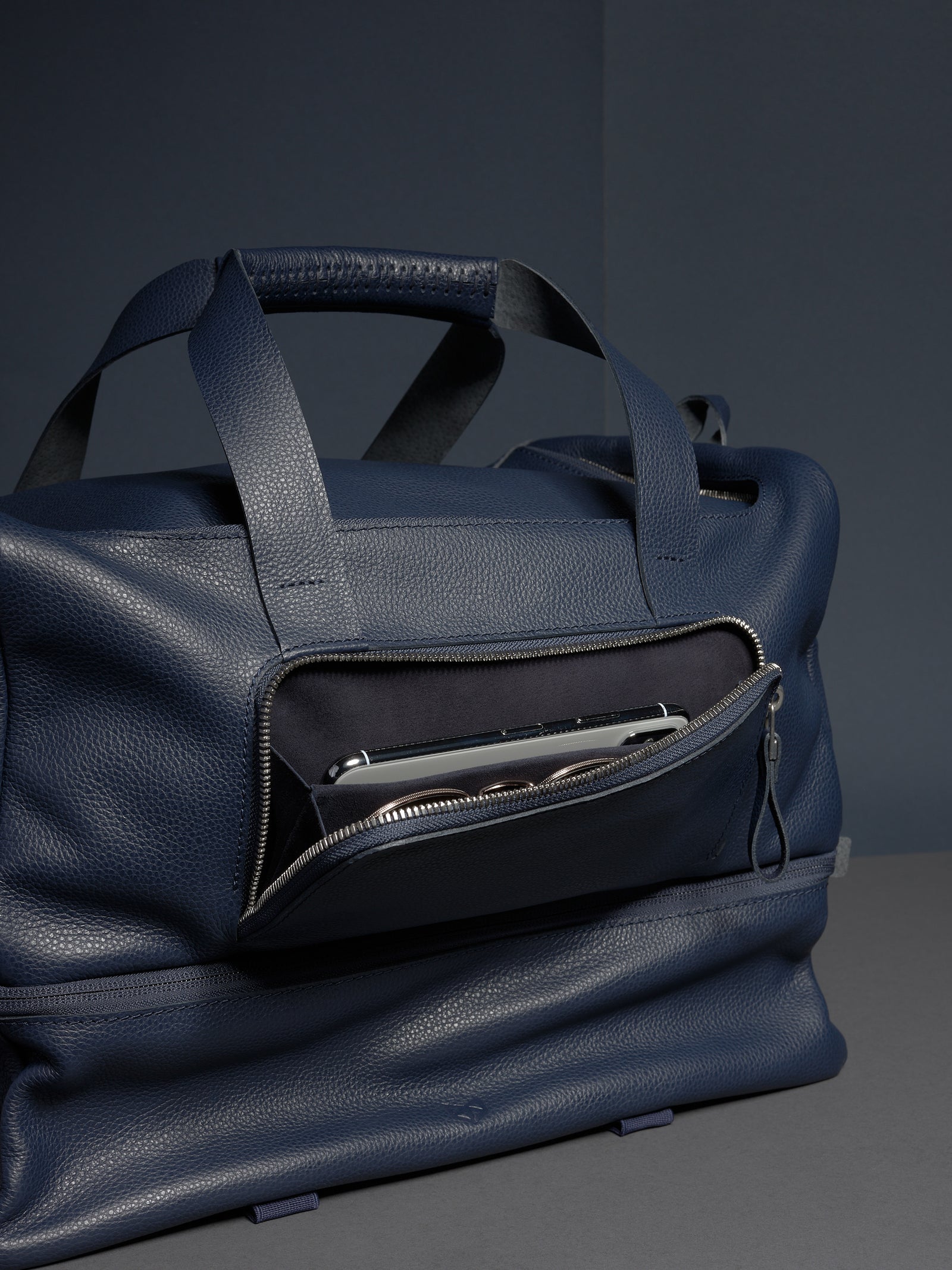 The Ventra Holdall bag with a front pocket unzipped, showing a smartphone and coins inside.