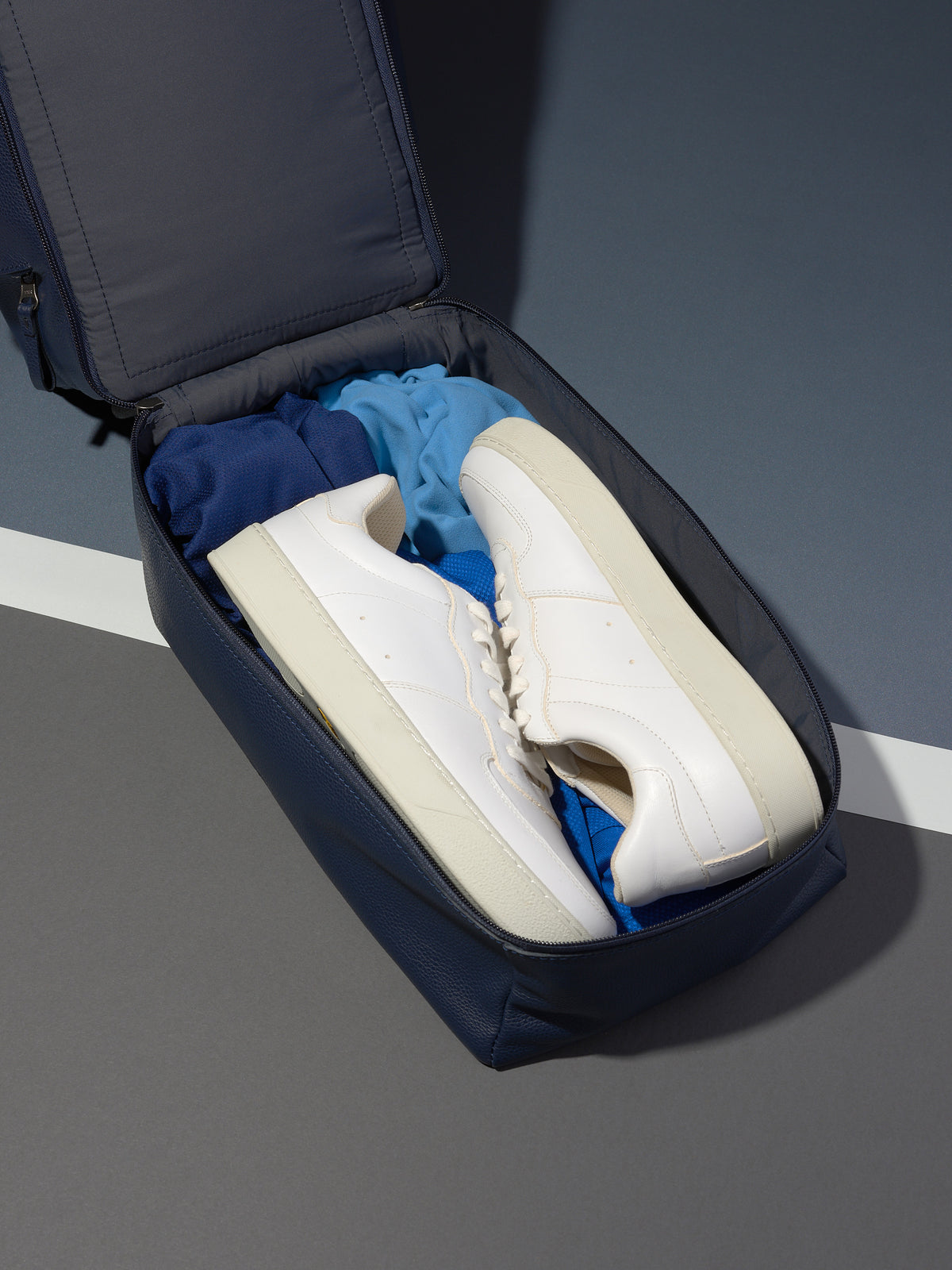 The Ventra Holdall bag with a lower compartment unzipped, revealing a pair of white sneakers.