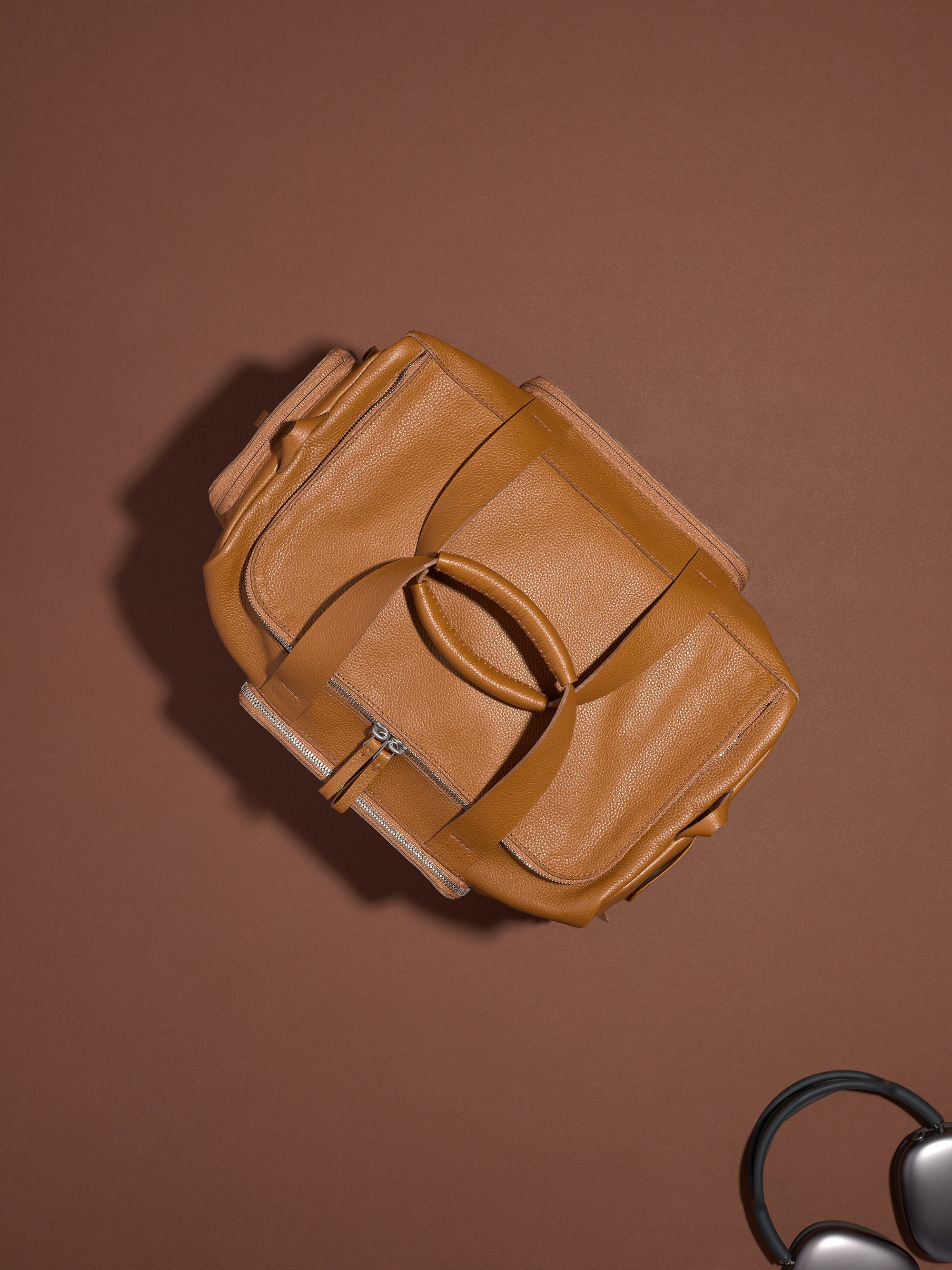 A top-down view of the tan leather Ventra Holdall, showing its elegant shape, handles, and pebbled texture.