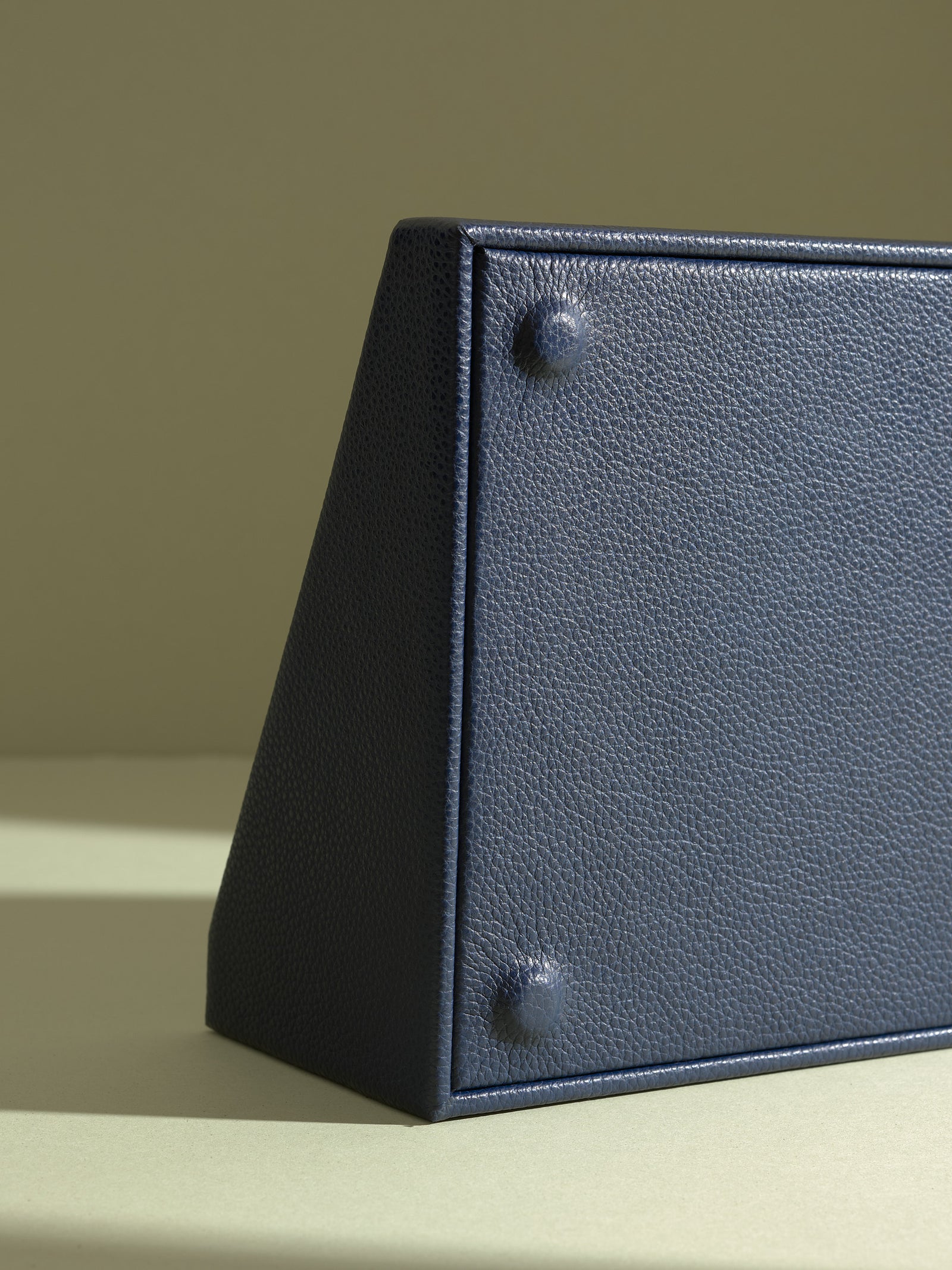 Close-up detail of the textured blue leather exterior and protective feet on the underside of a watch display drawer.
