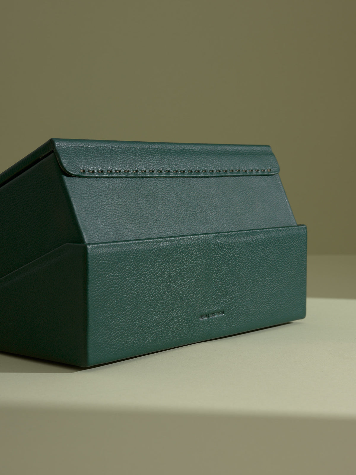 Back angle of the closed green leather watch box, showcasing the stitched spine and debossed Capra Leather logo.