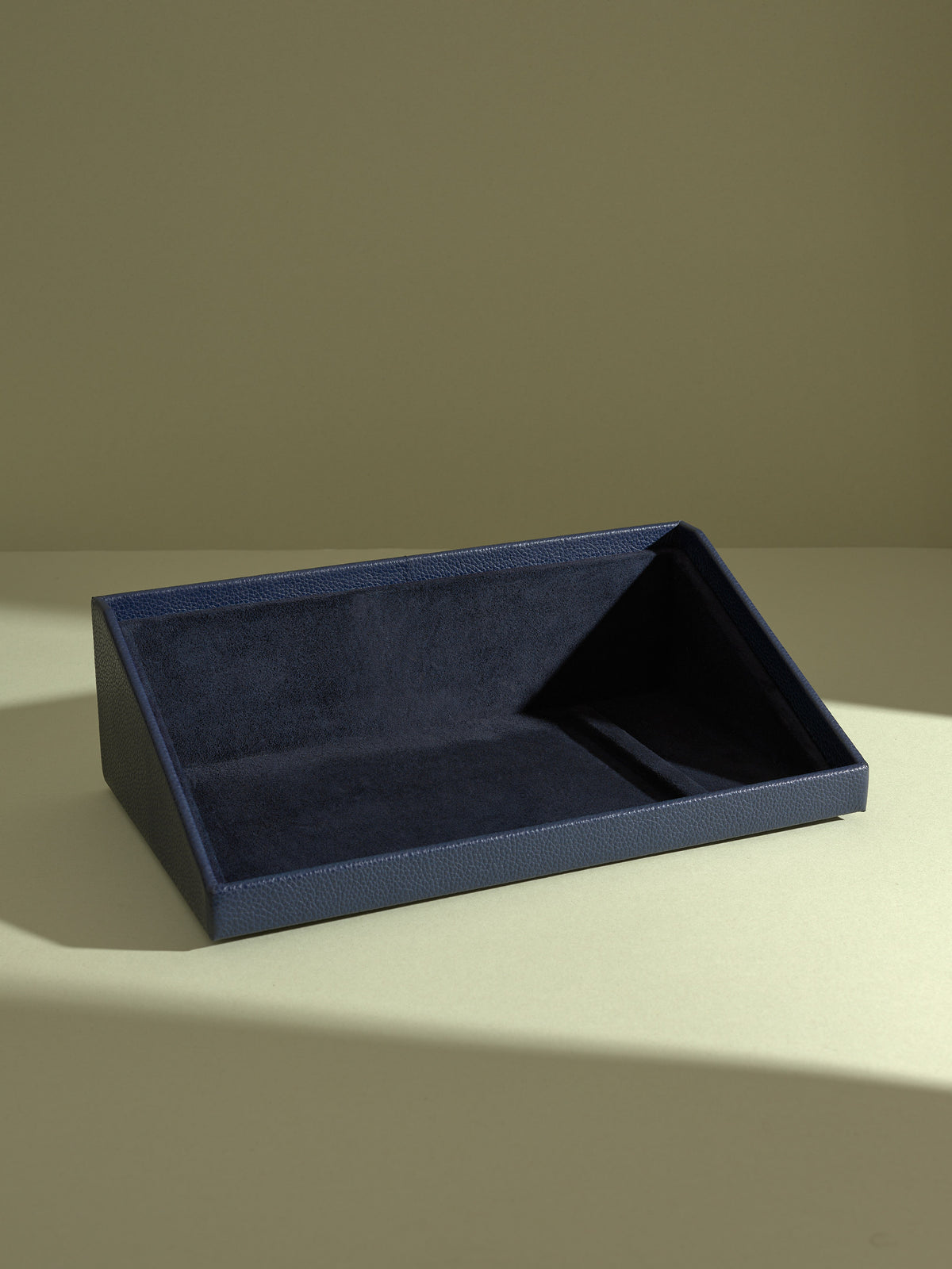 Front view of the empty navy blue leather angled display stand and valet drawer with a soft navy suede interior.