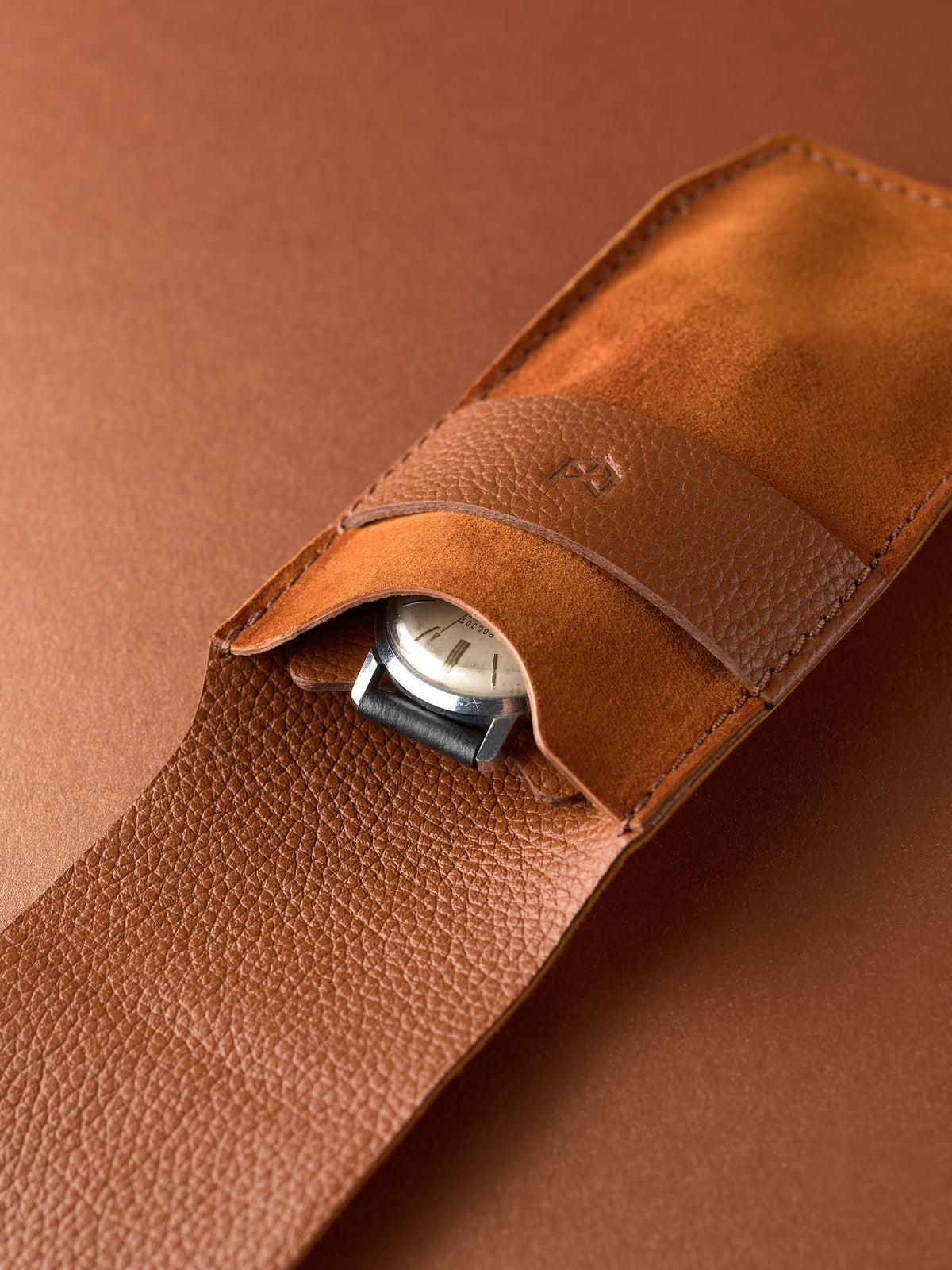 Close-up of a watch's face and strap safely stored inside a Capra Leather tan leather pouch.