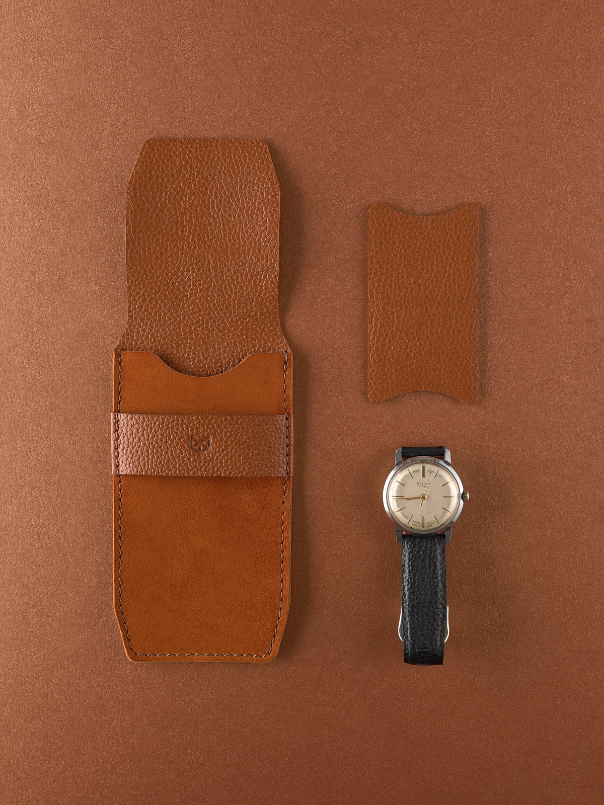 Top-down view of a closed Capra Leather tan leather watch pouch with a textured leather band.