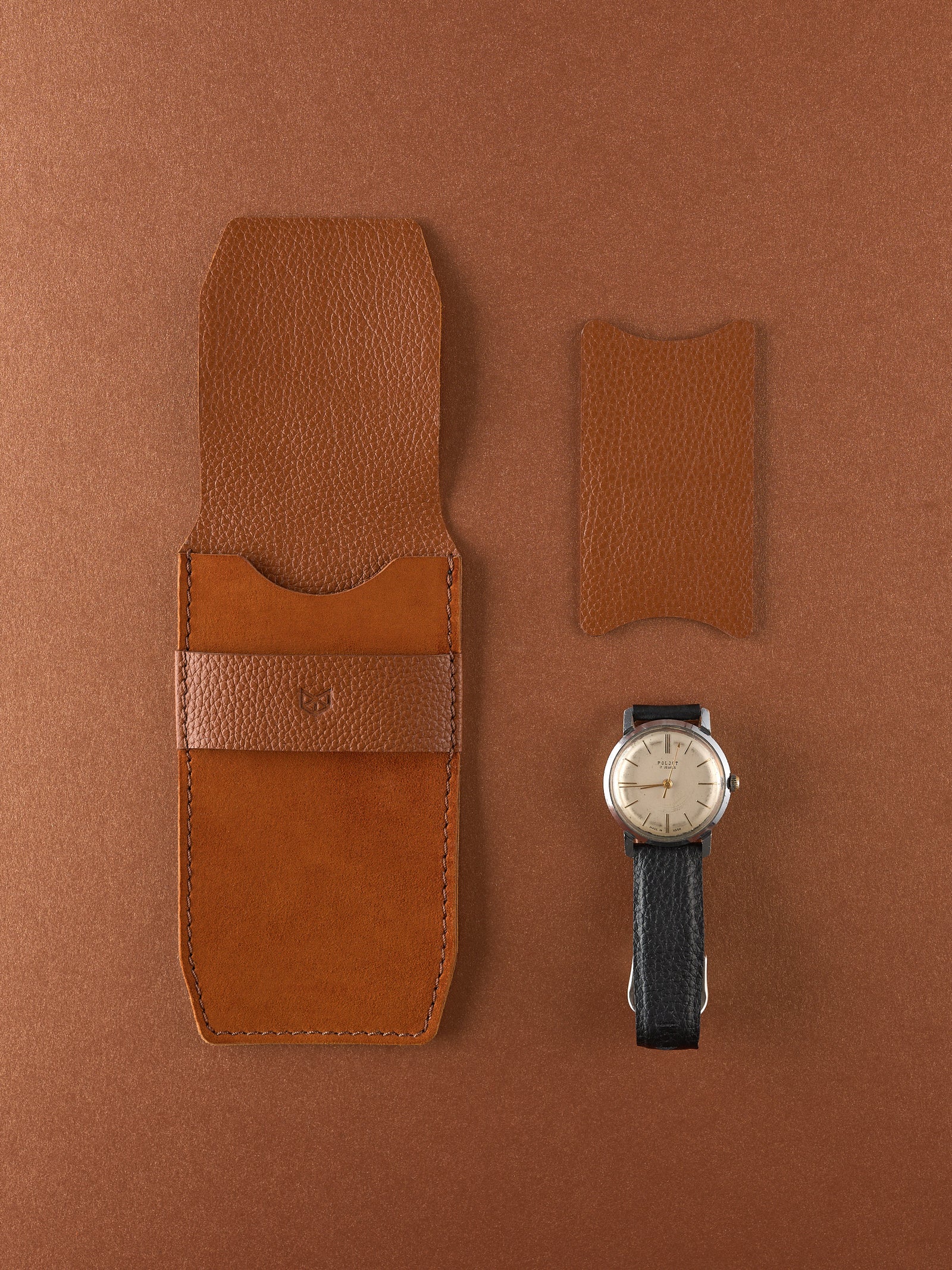 Top-down view of a closed Capra Leather tan leather watch pouch with a textured leather band.