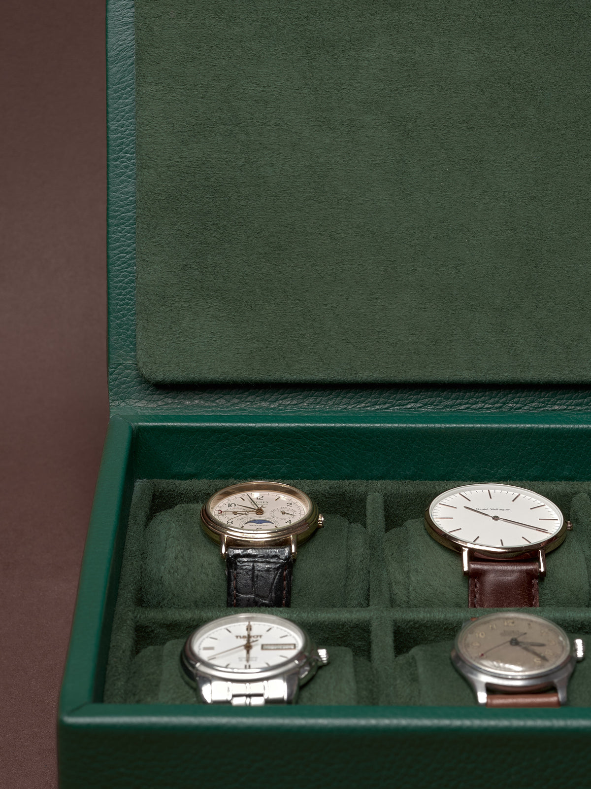 Open green leather watch box by Capra Leather, displaying several classic watches.