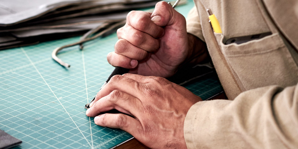 Hands cutting leather along a steel ruler for a made-to-order Capra Leather piece