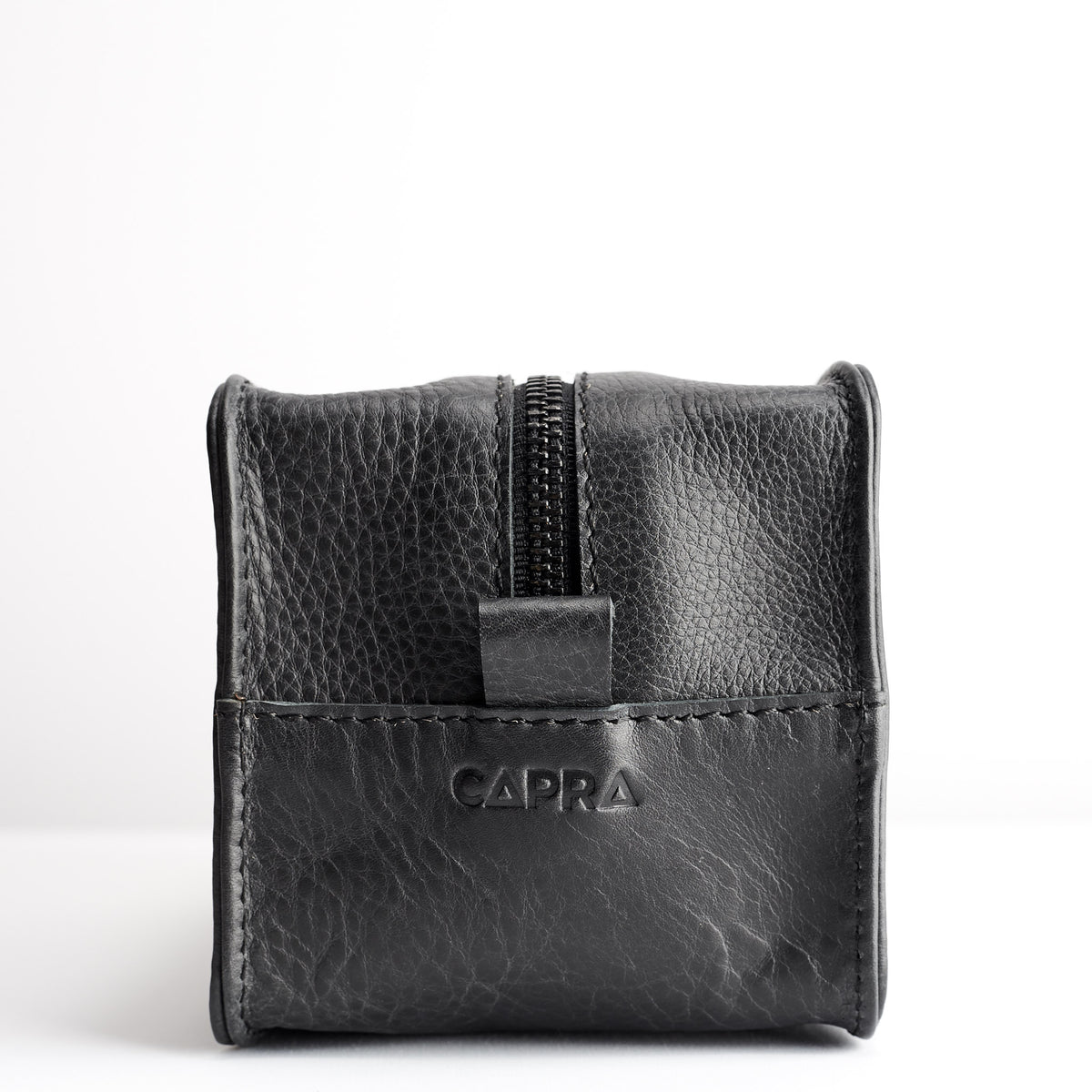 Detail. Capra Leather logo engraving. Black leather barber dopp kit for men