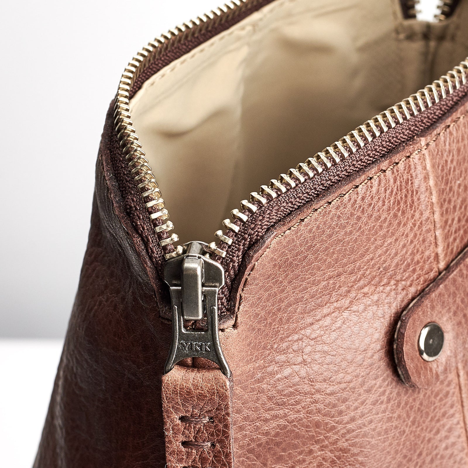 Has stitched pull tabs. Brown leather waterproof dopp kit for men