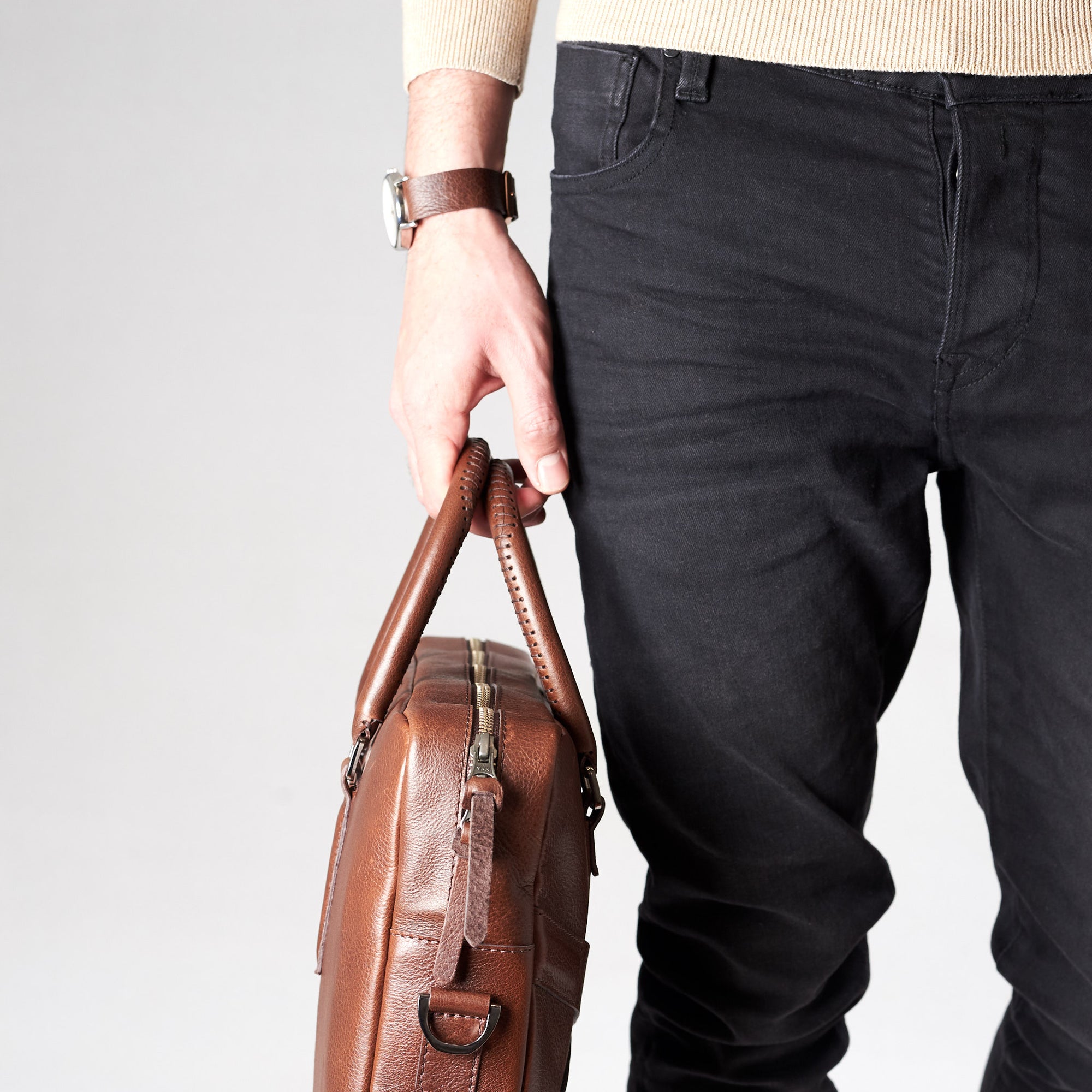 Style side view of model holding workbag. Brown leather briefcase laptop bag for men. Gazeli laptop briefcase by Capra Leather.