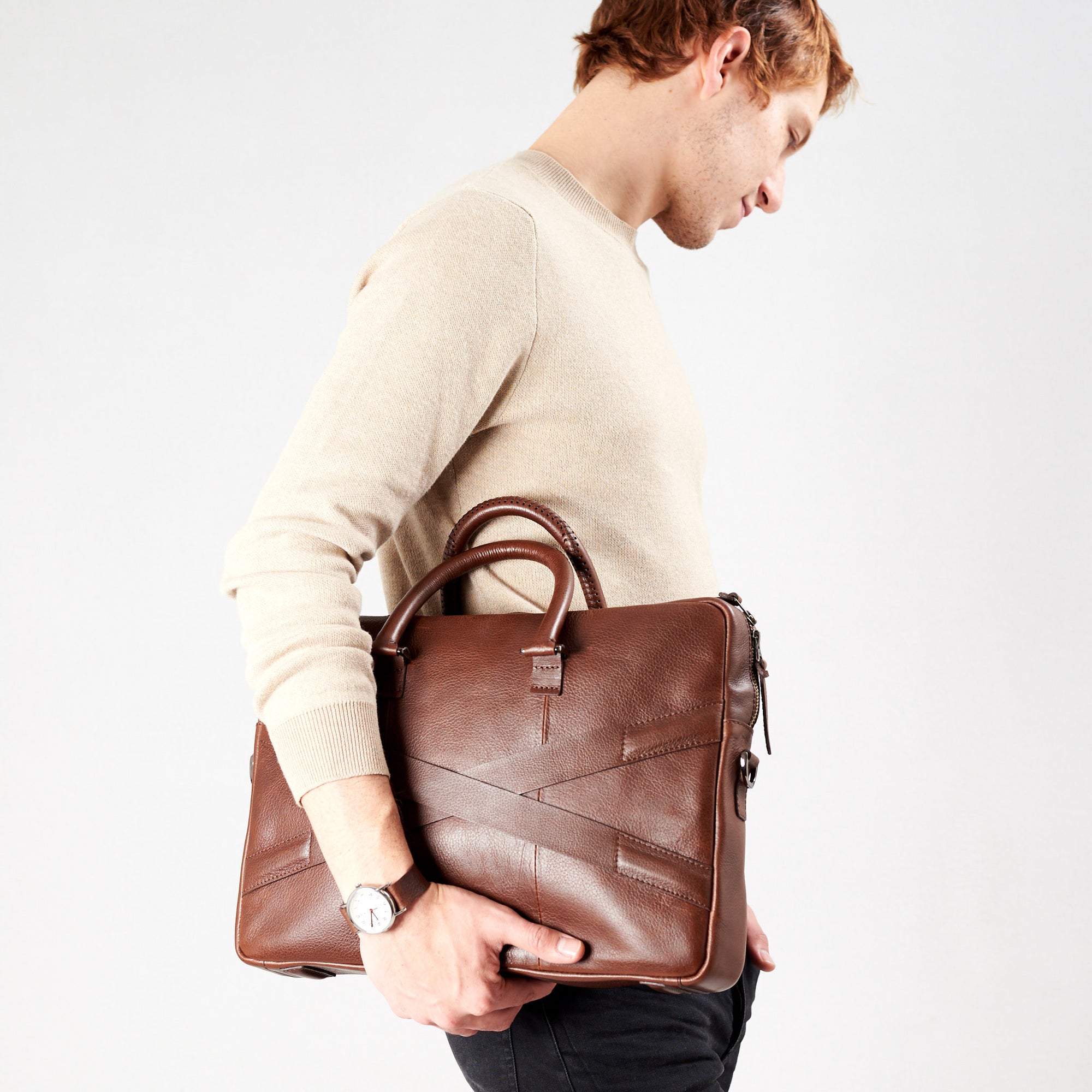 Style model holding crossbody with hands. Brown leather briefcase laptop bag for men. Gazeli laptop briefcase by Capra Leather.