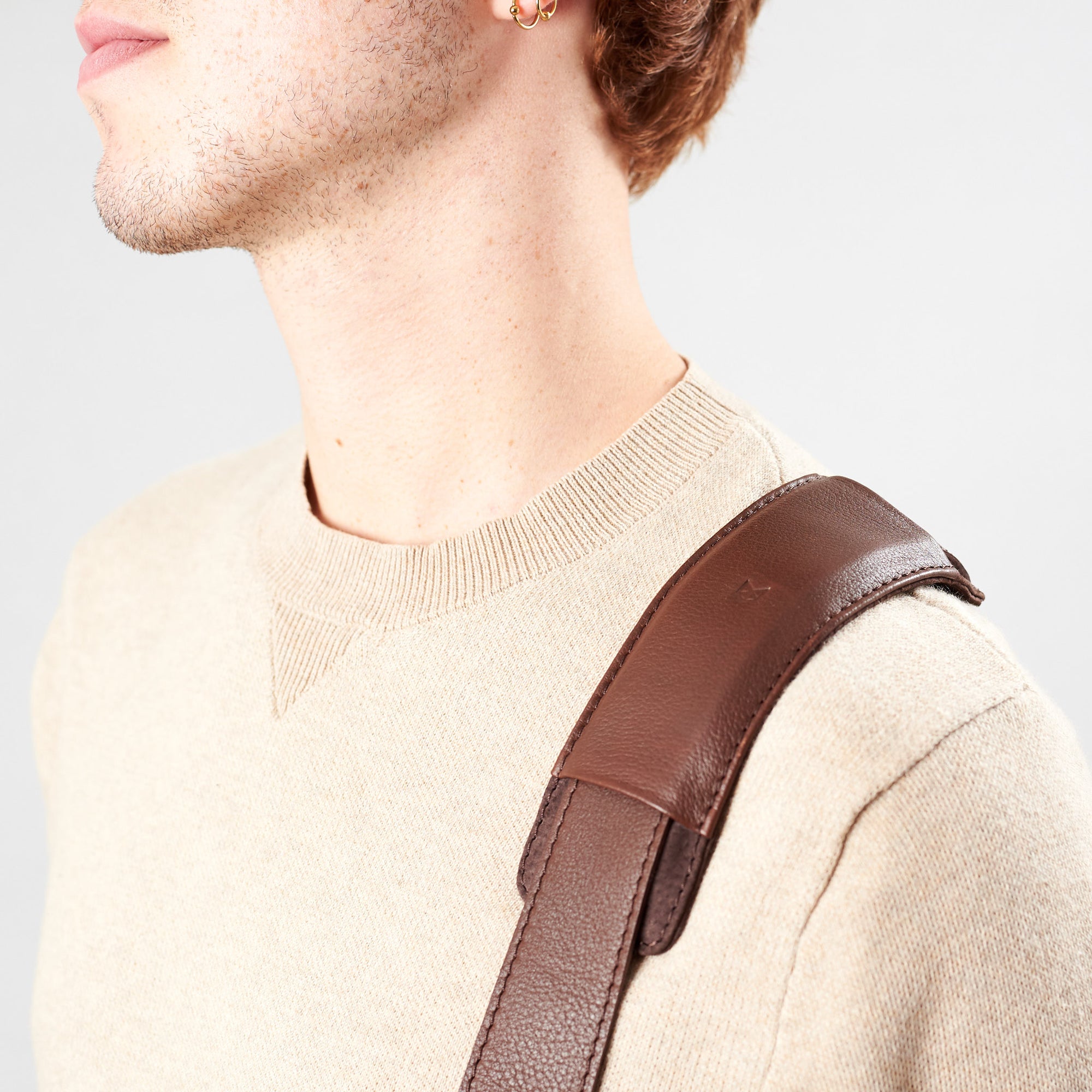 Detail of model wearing minimalist strap design. Brown leather briefcase laptop bag for men. Gazeli laptop briefcase by Capra Leather.