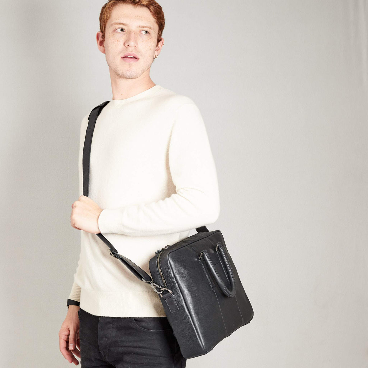 Style side view of model holding workbag. Black leather briefcase laptop bag for men. Gazeli laptop briefcase by Capra Leather.