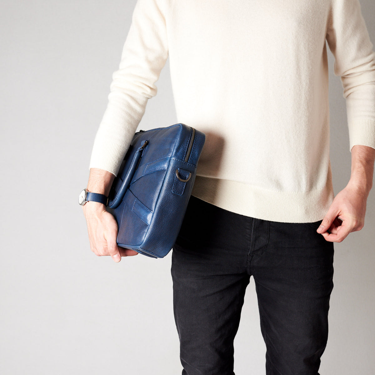 Style model holding crossbody with hands. Blue leather briefcase laptop bag for men. Gazeli laptop briefcase by Capra Leather.