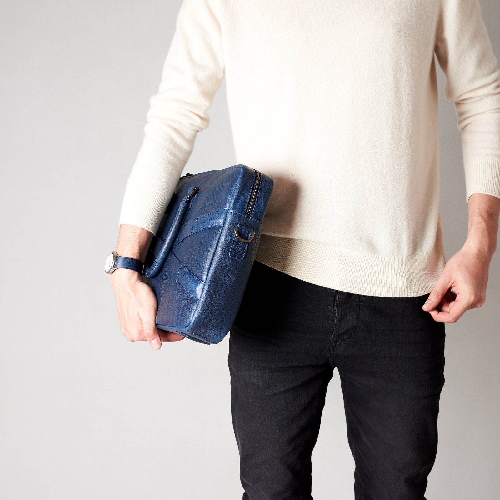 Style model holding crossbody with hands. Blue leather briefcase laptop bag for men. Gazeli laptop briefcase by Capra Leather.