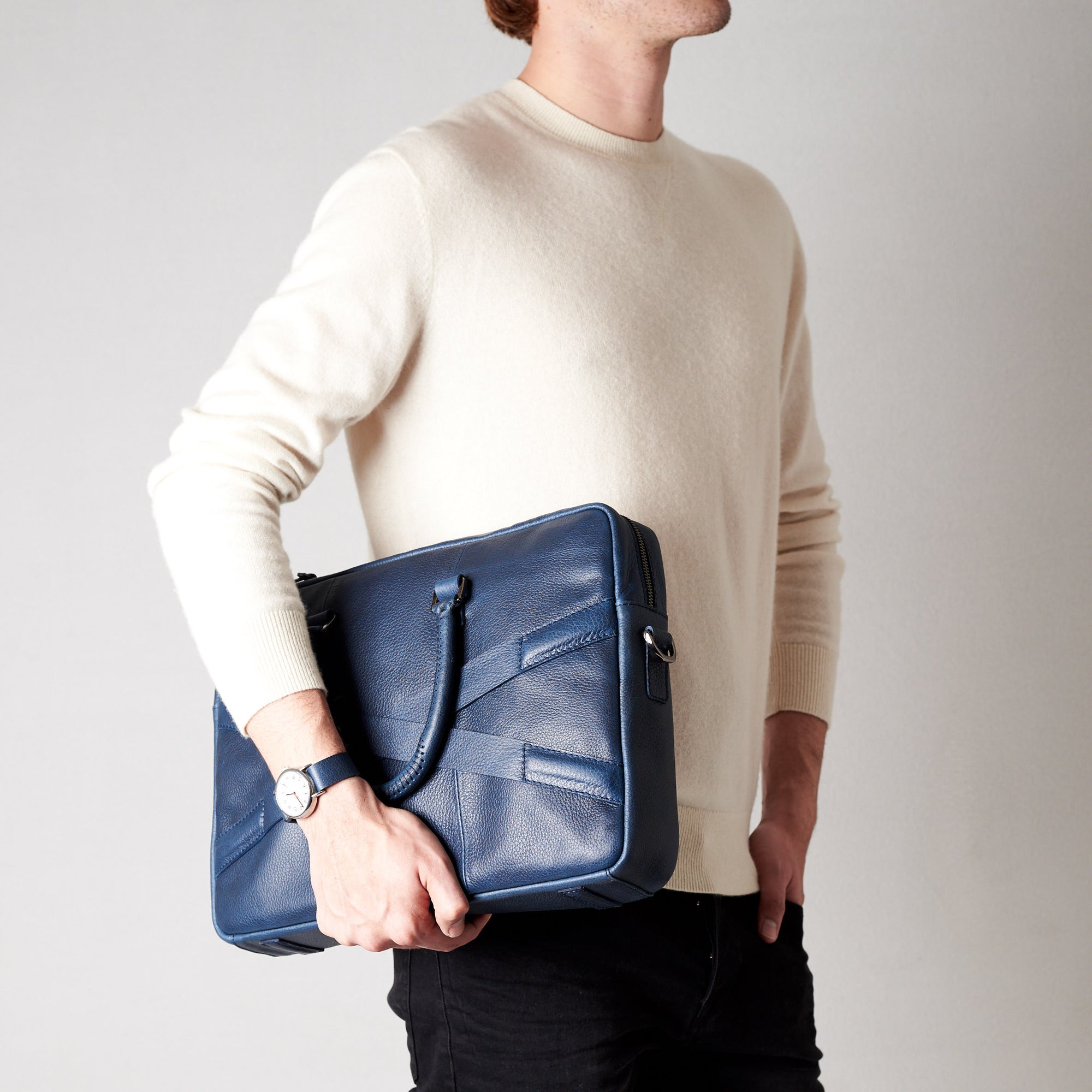 Style side view of model holding workbag. Blue leather briefcase laptop bag for men. Gazeli laptop briefcase by Capra Leather.