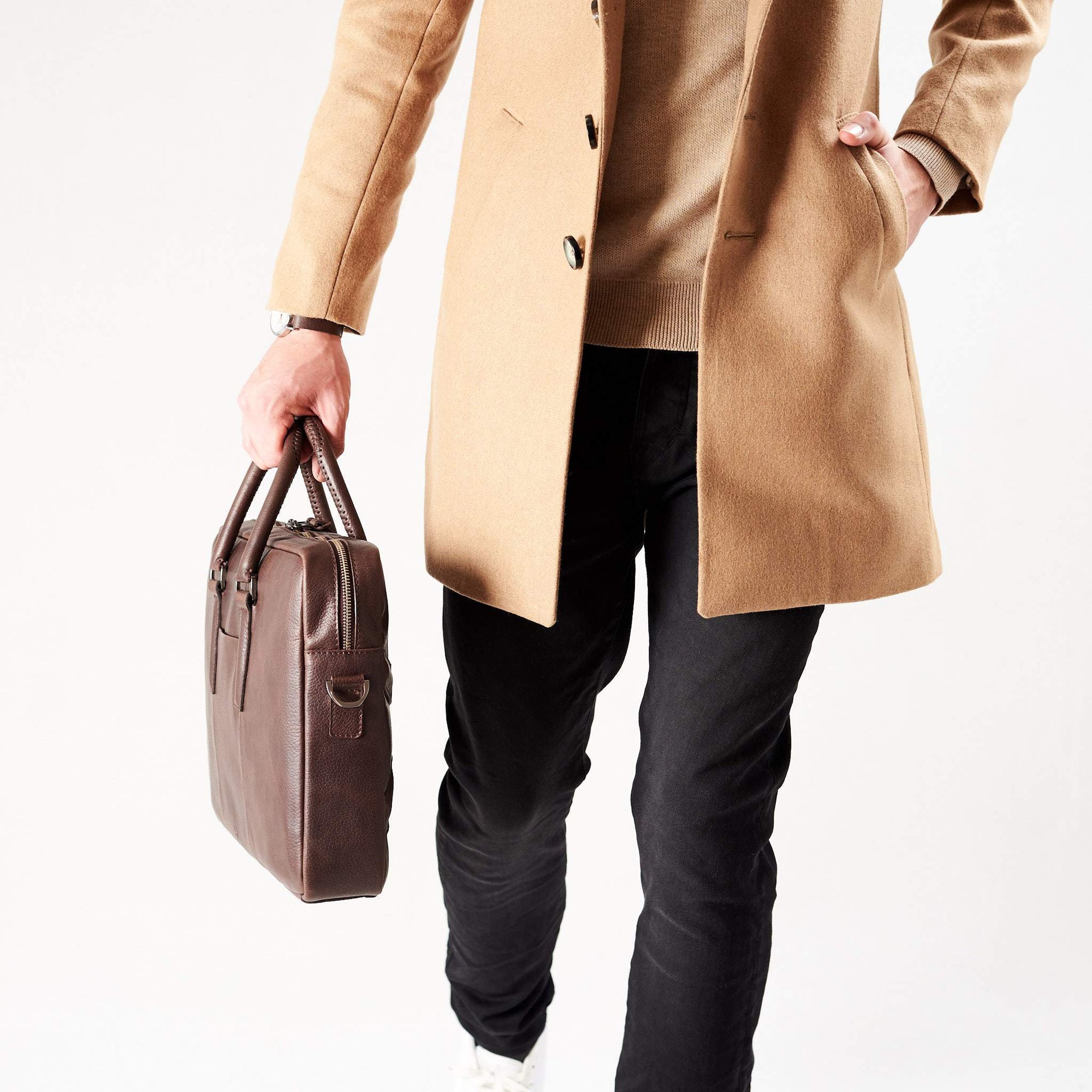 Style side view of model holding workbag. Dark Brown leather briefcase laptop bag for men. Gazeli laptop briefcase by Capra Leather.