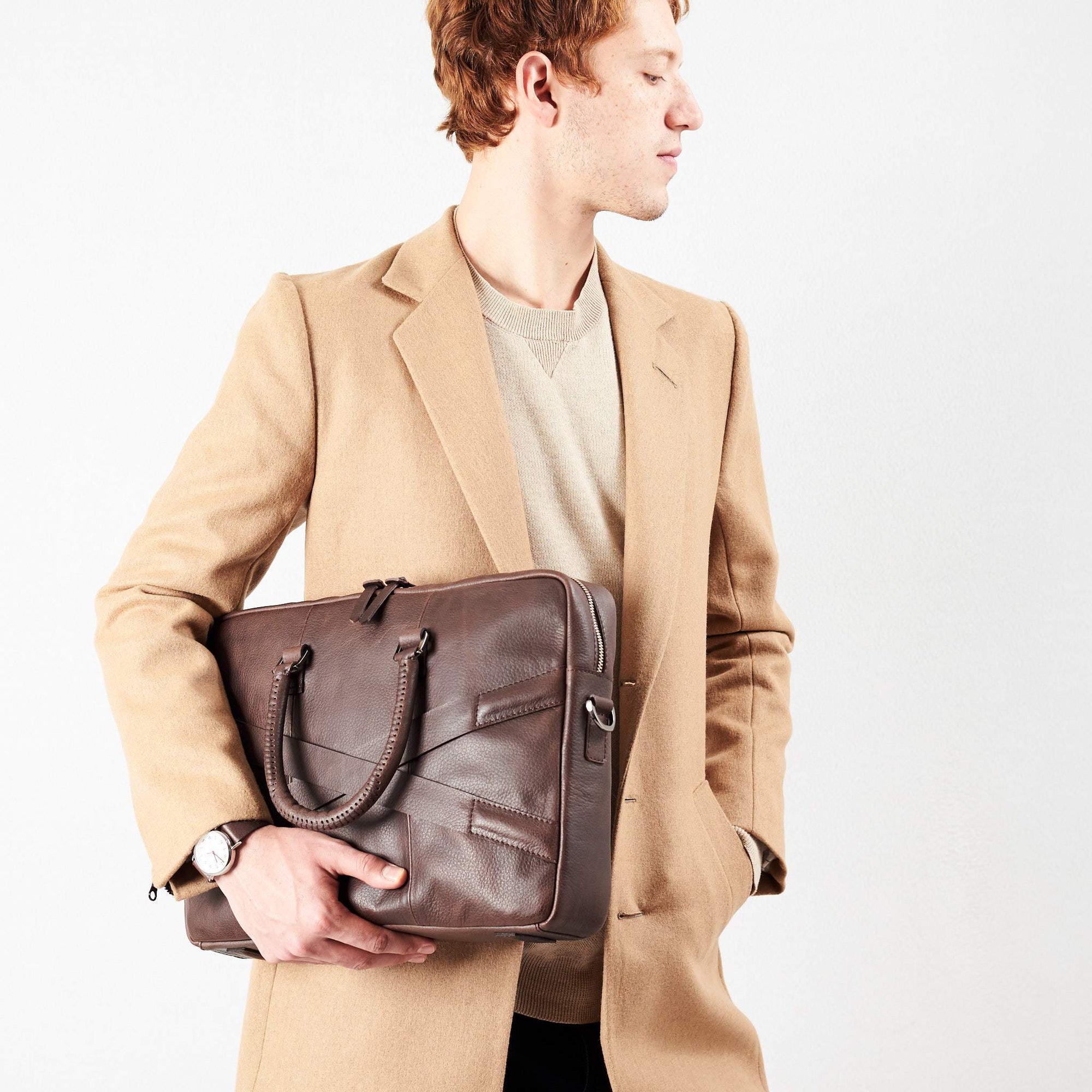Style model holding crossbody with hands. Dark Brown leather briefcase laptop bag for men. Gazeli laptop briefcase by Capra Leather.