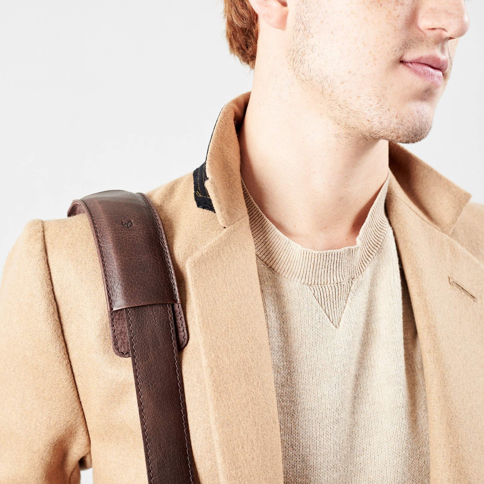 Detail of model wearing minimalist strap design. Dark Brown leather briefcase laptop bag for men. Gazeli laptop briefcase by Capra Leather.