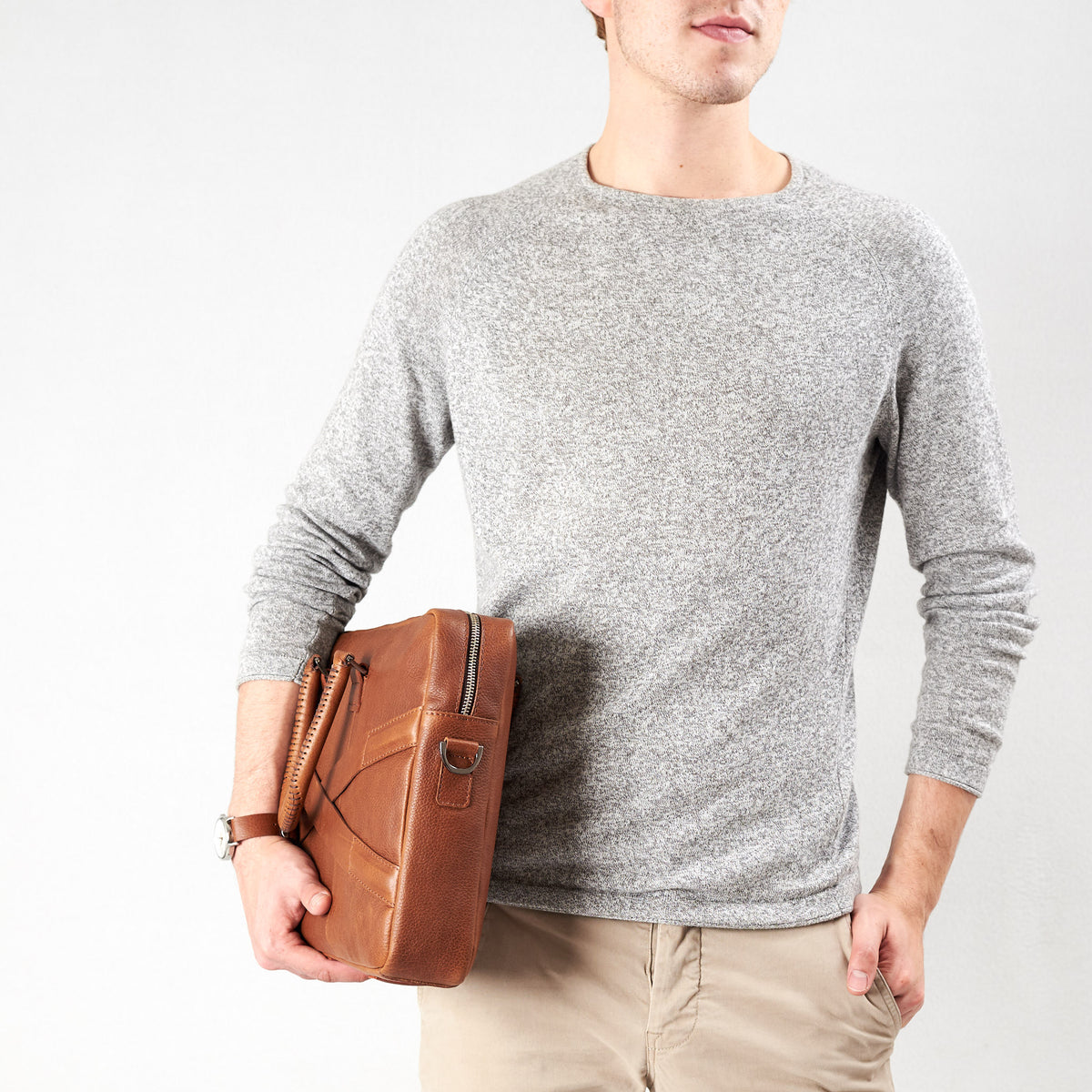 Style model holding crossbody with hands. Tan leather briefcase laptop bag for men. Gazeli laptop briefcase by Capra Leather.
