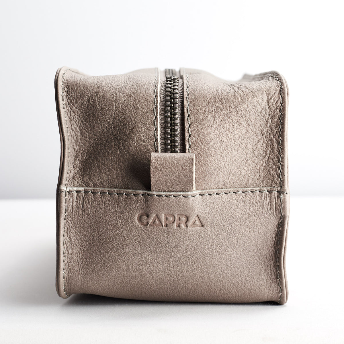 detail. Capra Leather logo engraving. Grey leather barber dopp kit for men