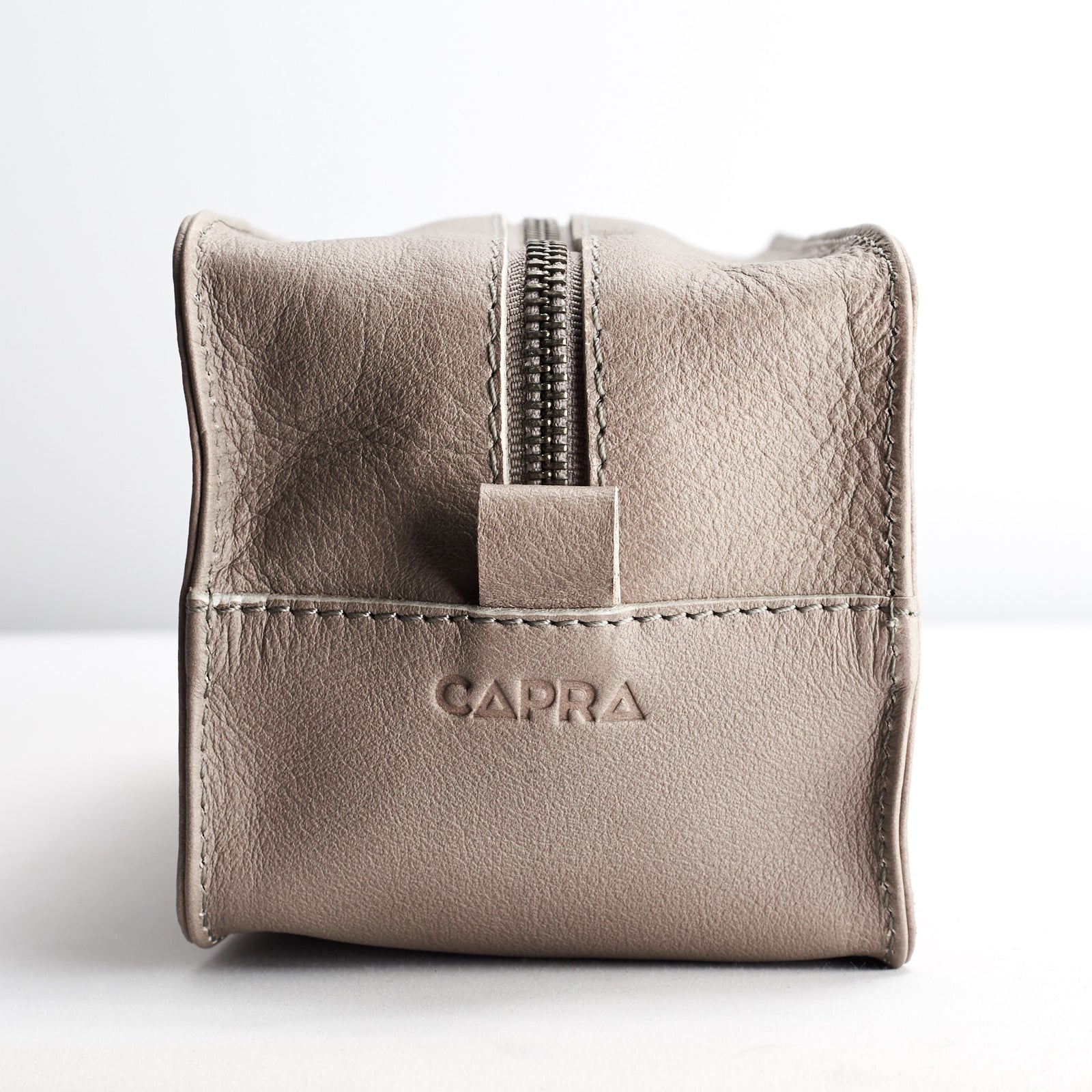 detail. Capra Leather logo engraving. Grey leather barber dopp kit for men