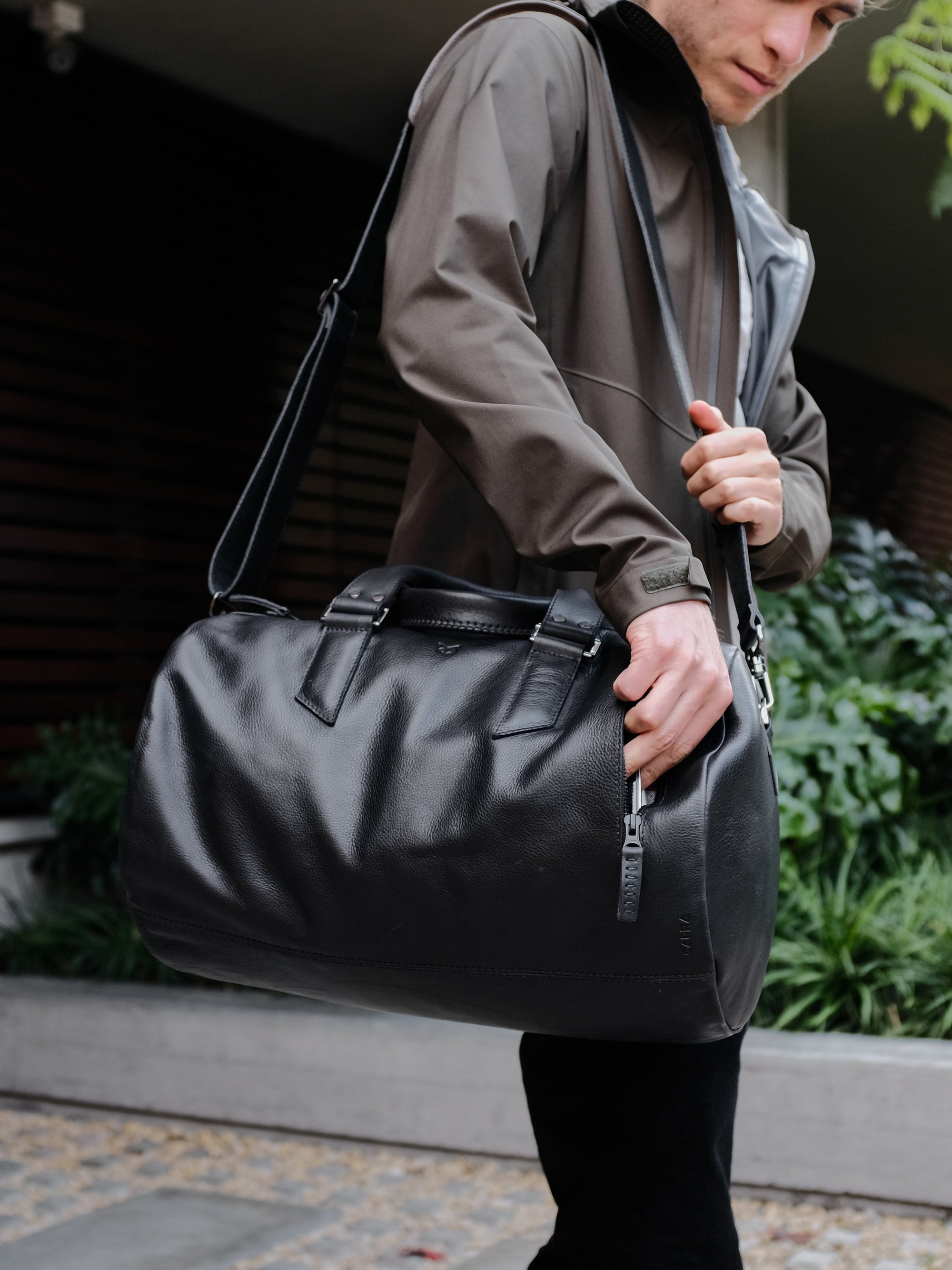 Style outside photo. Black leather duffle handbag for men. Travel designer bag 