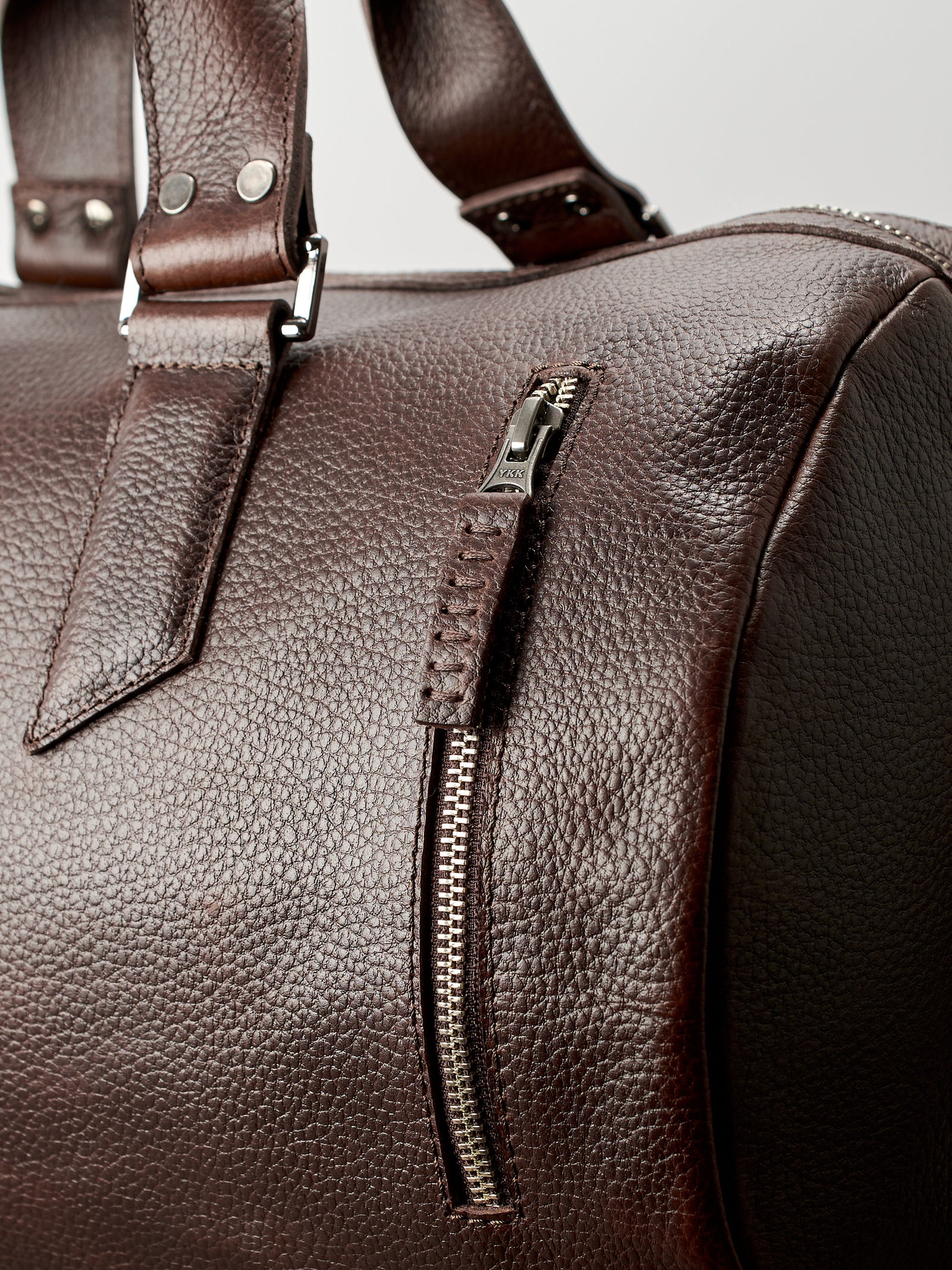 YKK metallic zippers. Dark brown leather carryall bag. Mens travel weekender bag
