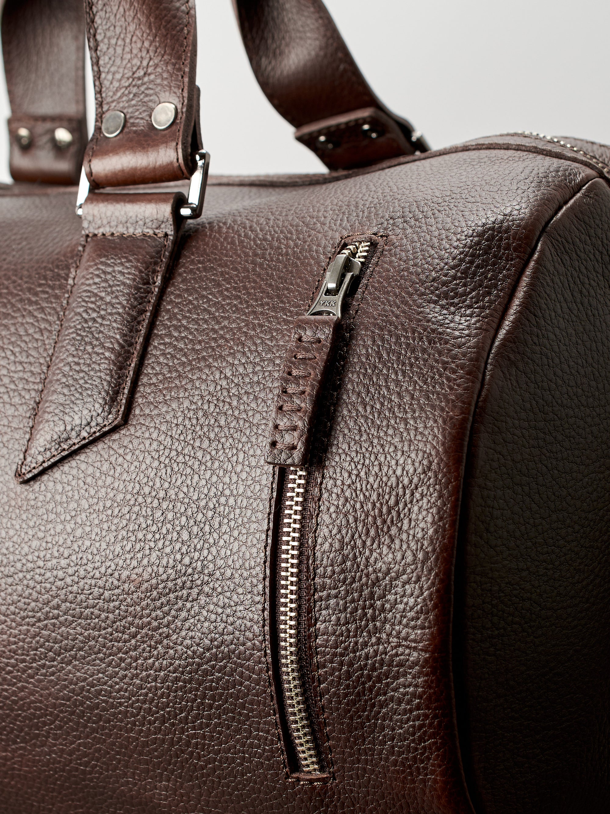 YKK metallic zippers. Dark brown leather carryall bag. Mens travel weekender bag