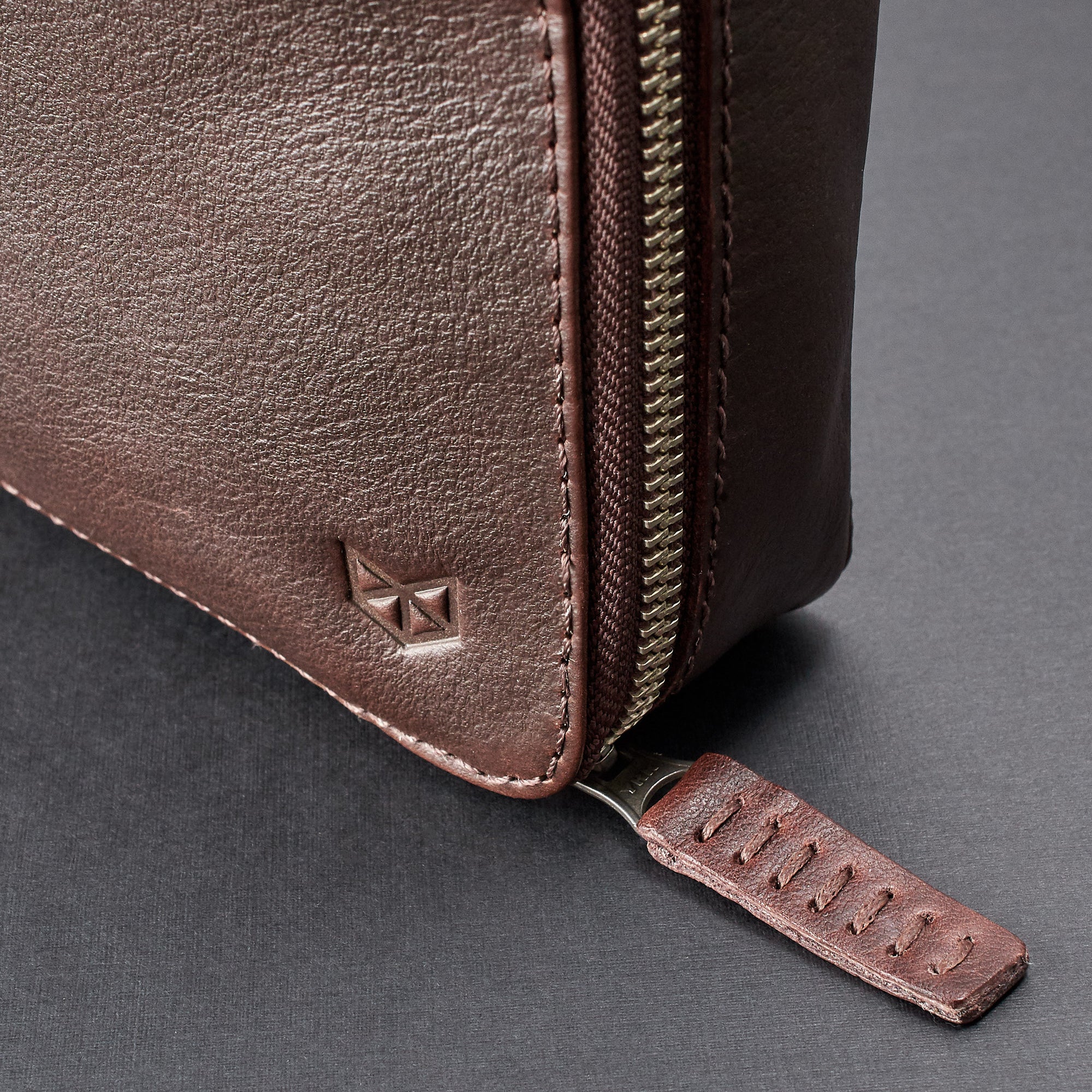 Hand stitched pull tabs. Dark brown travel gadget bag by Capra Leather